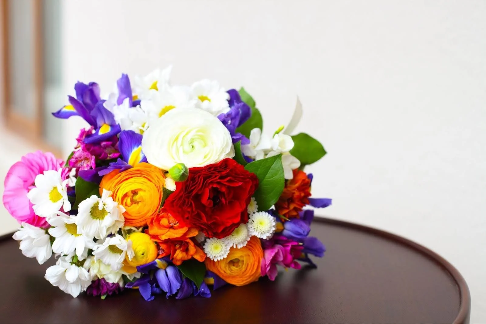 A brightly colored wedding bouquet resting on a dark wooden table