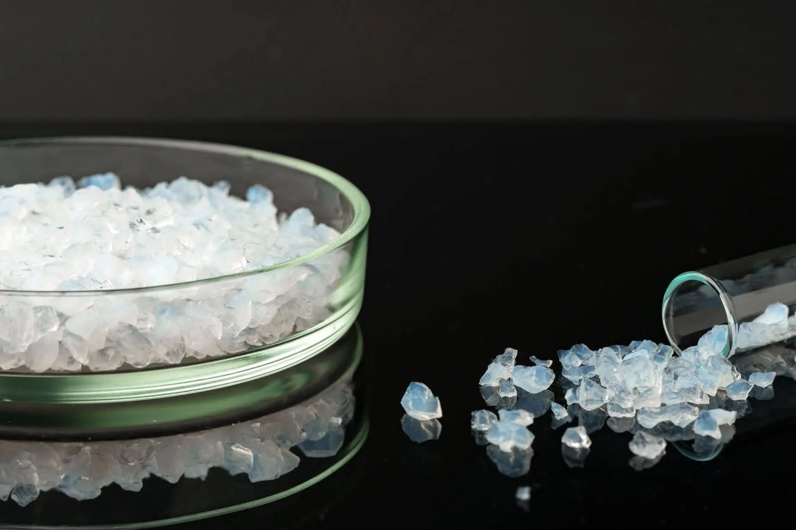 A glass petri dish filled with translucent silica gel crystals