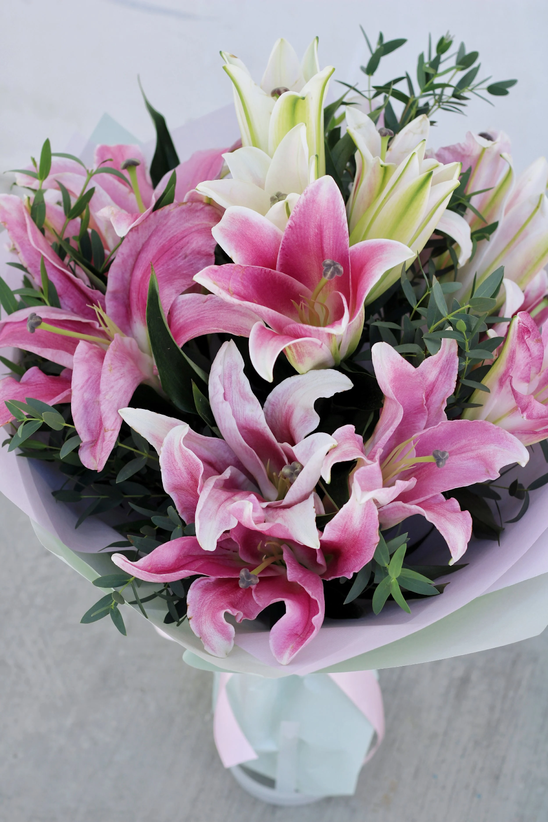 A lush bouquet of large pink and white lilies mixed with eucalyptus