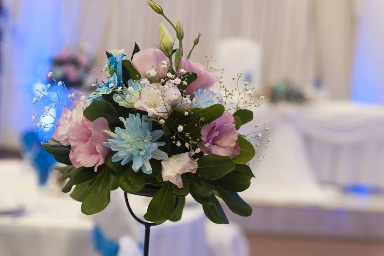 A tall floral wedding centerpiece on a thin black stand