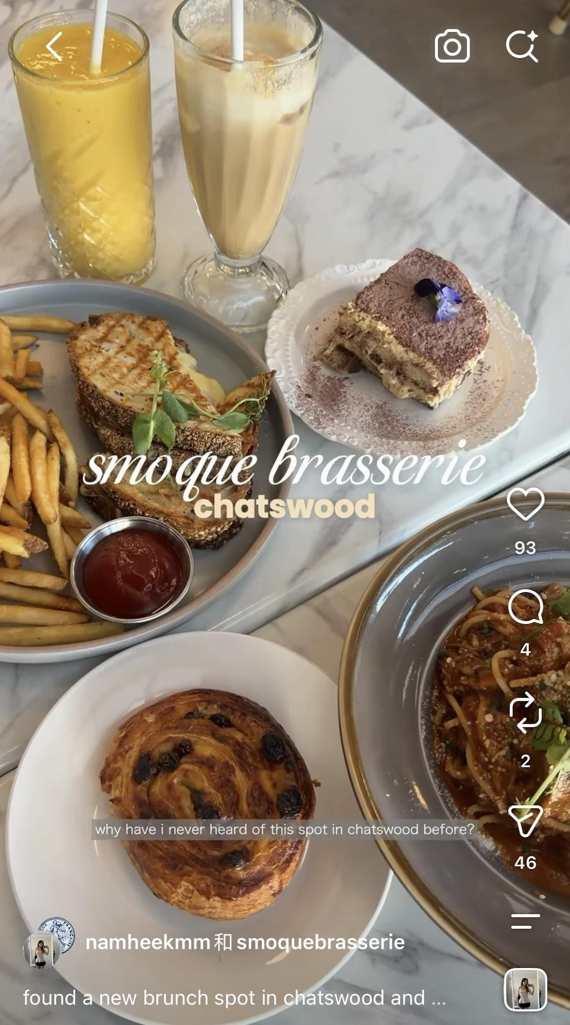 A variety of brunch foods including French fries, a grilled cheese sandwich, a raisin Danish pastry, a slice of tiramisu, a bread roll, a bowl of pasta, and two drinks: orange juice and a milkshake, on a marble table.