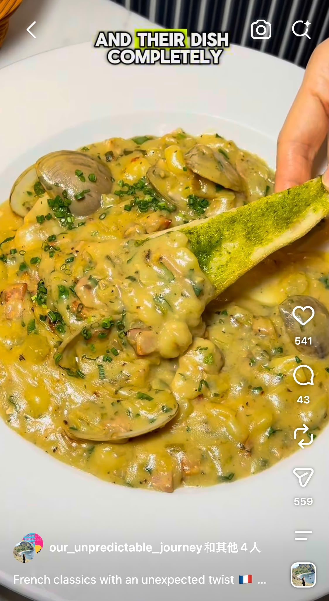 Close-up of a bowl of creamy seafood dish with clams and chopped herbs, with a slice of lime or lemon.