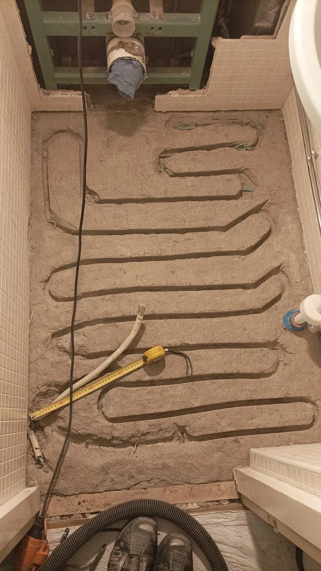 Saneerausvaiheessa oleva kylpyhuoneen lattiamaalaus, jossa näkyy lattialämmitysputkien kaivaminen esiin betonista.