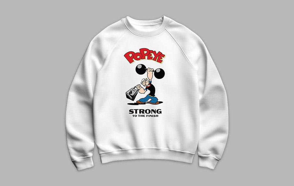 White sweatshirt featuring a graphic of Popeye lifting a dumbbell, with the text 'POPEYE' at the top and 'STRONG TO THE FINISH' below.
