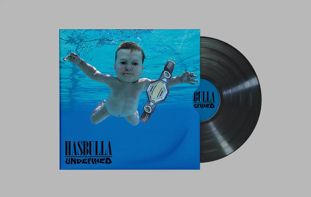 An album cover featuring a baby submerged in water, holding a championship belt, with a vinyl record beside it. The album title is