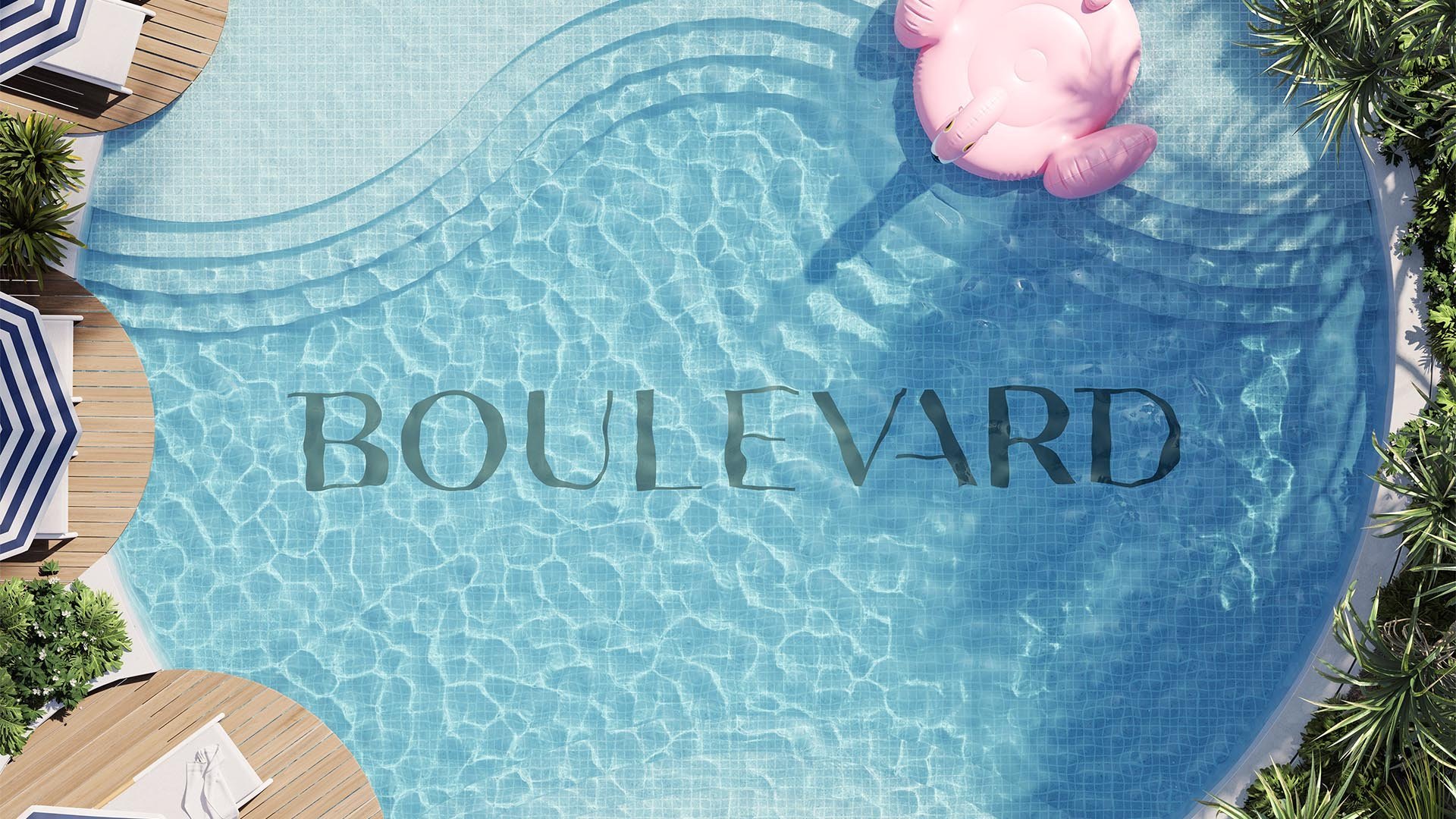 An overhead view of a swimming pool with a pink flamingo float, the word "BOULEVARD" written across the water, surrounded by lounge chairs, umbrellas, and tropical plants.