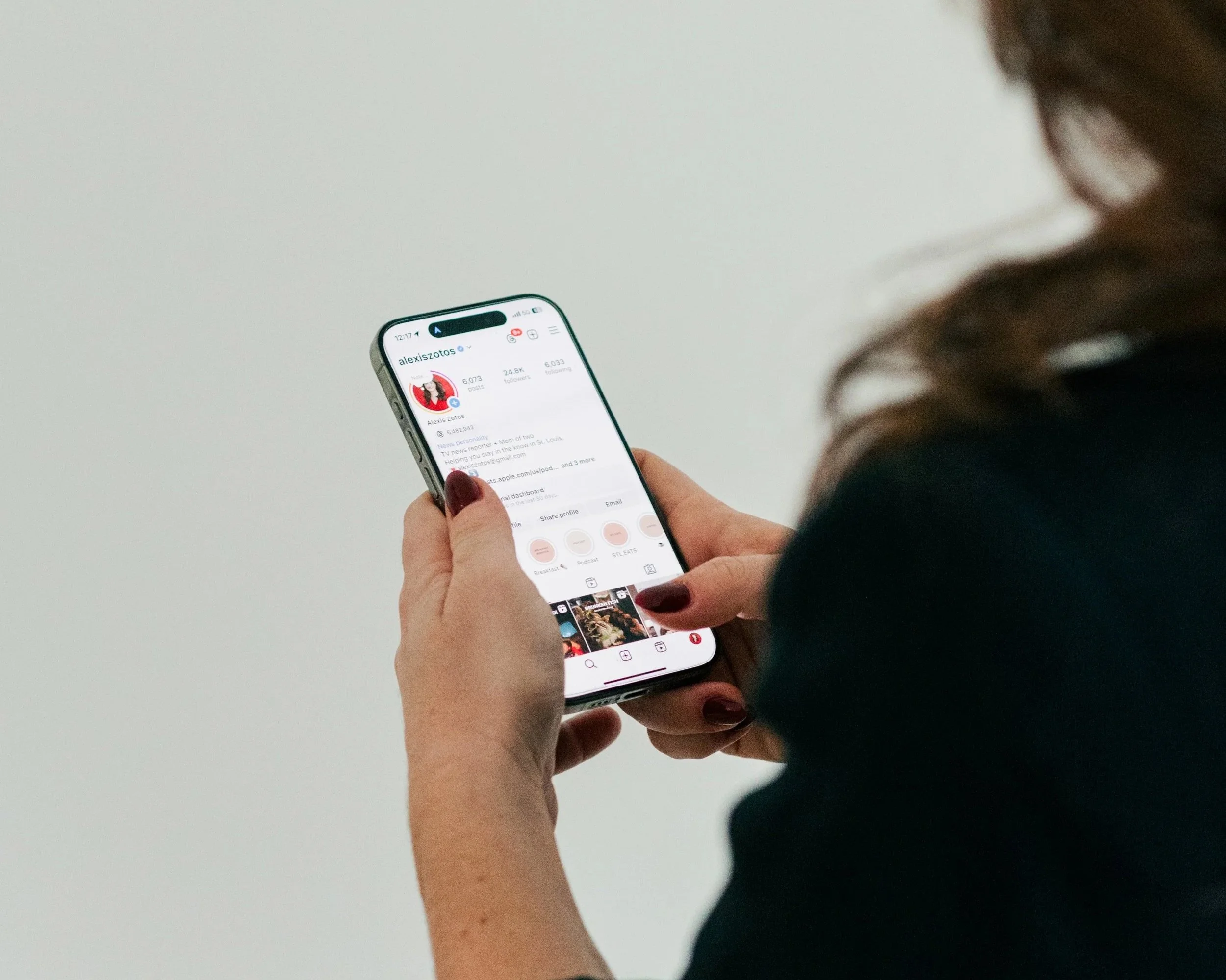Person holding a smartphone, viewing an Instagram profile.