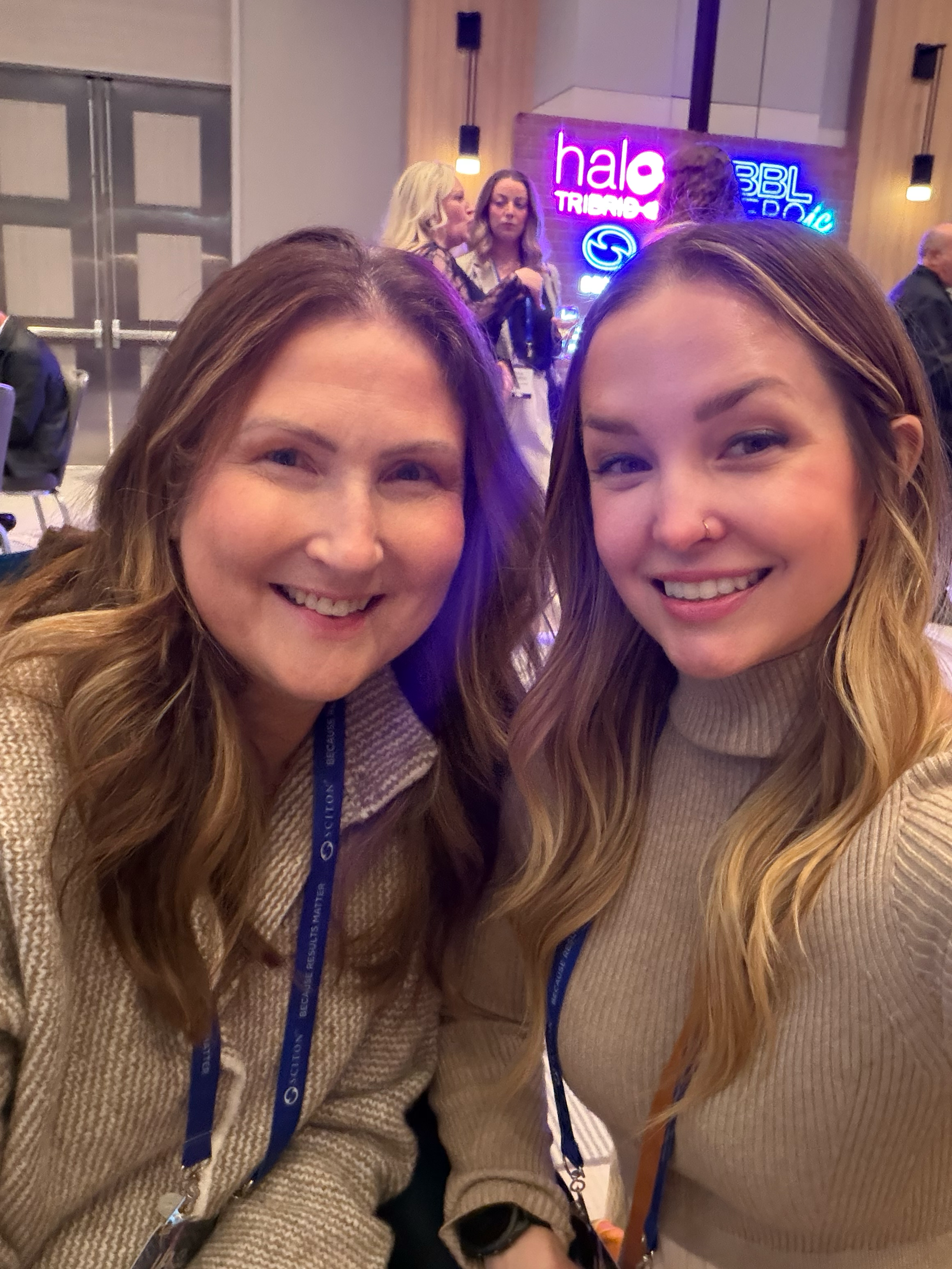 A candid photo of two smiling Harmony Wellness team members together at an event