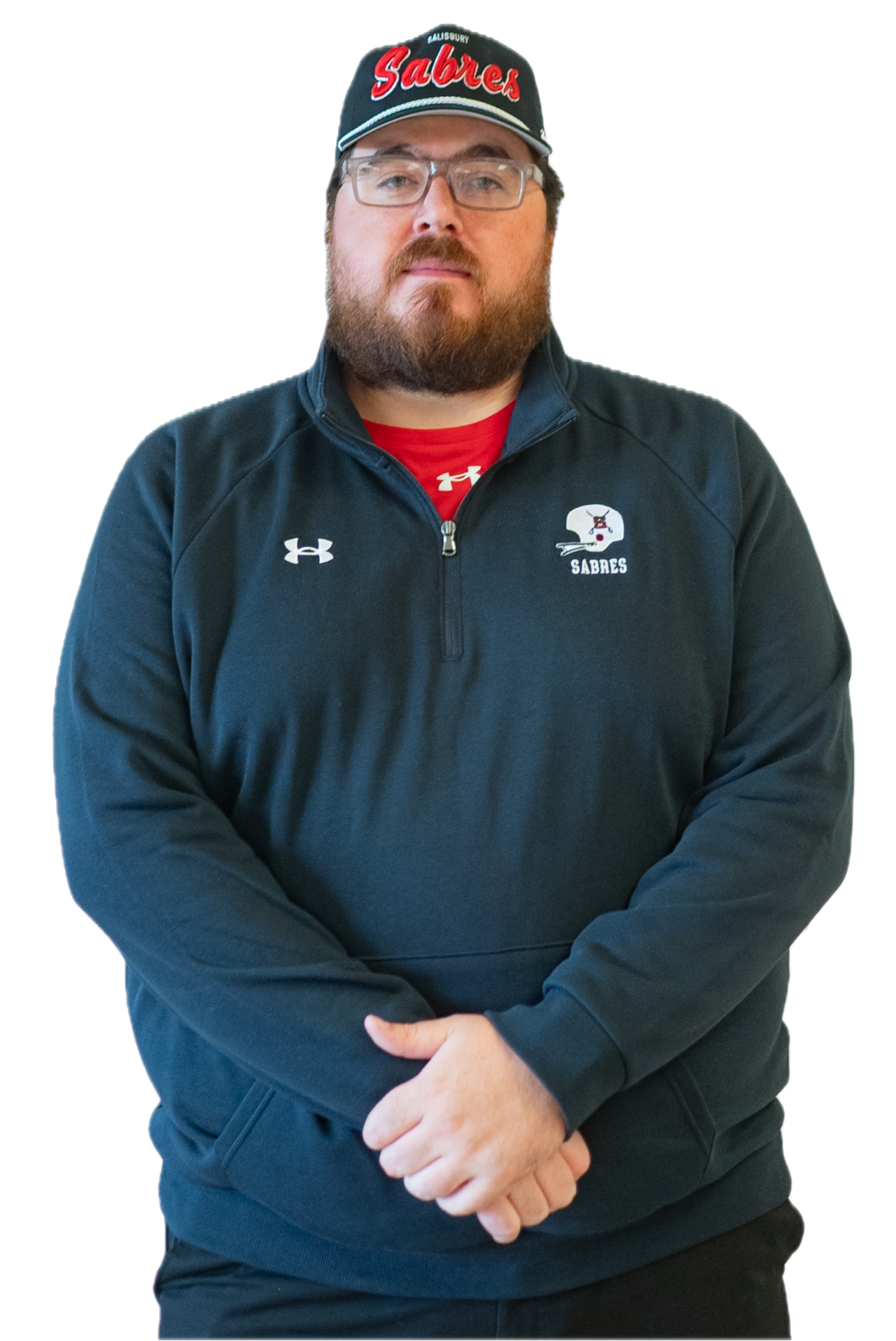A man with dark hair and glasses, wearing a Salisbury Sabres Football t-shirt, standing against a brick wall.