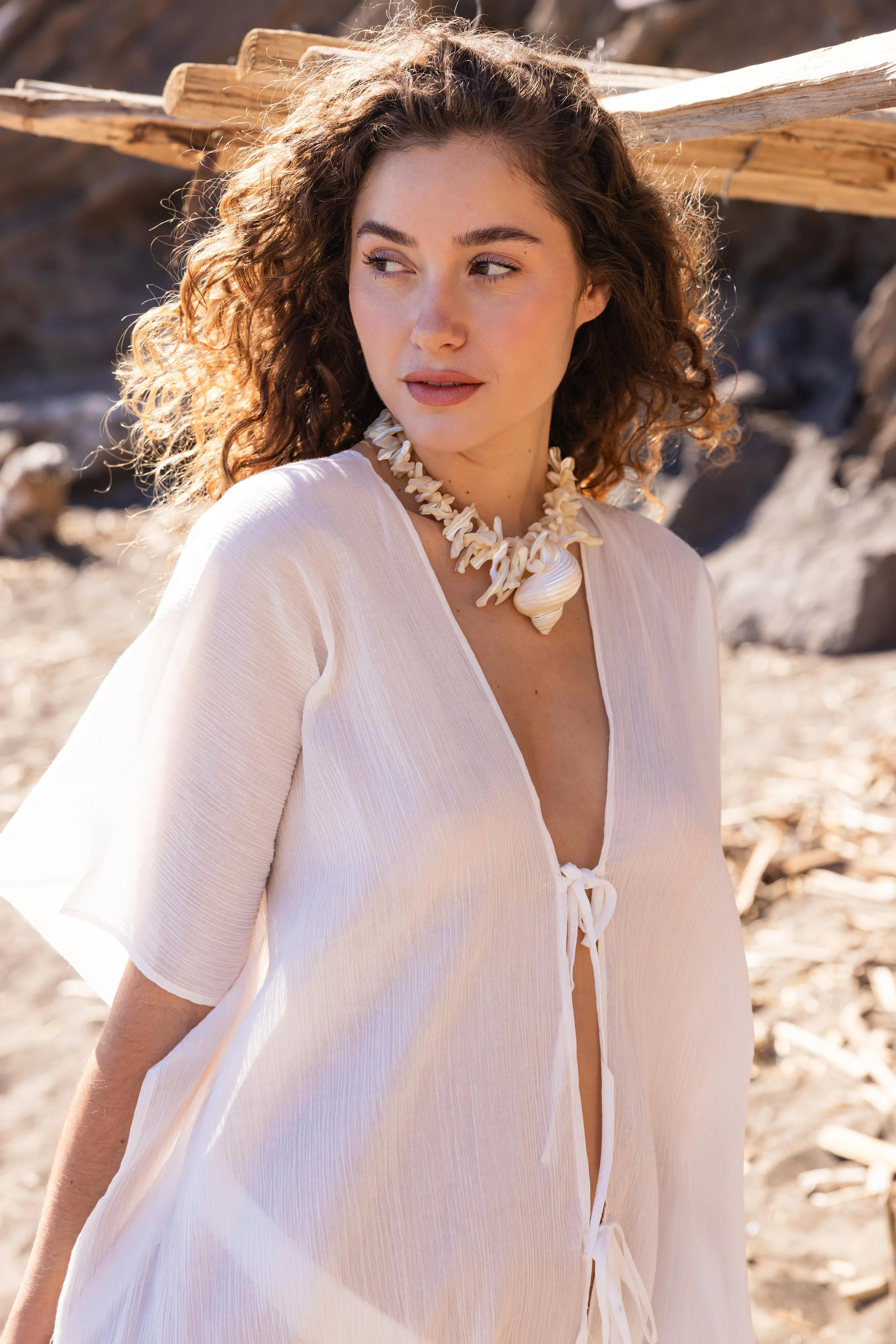 Portrait d'une mannequin avec un collier coquillage sur une plage rocheuse