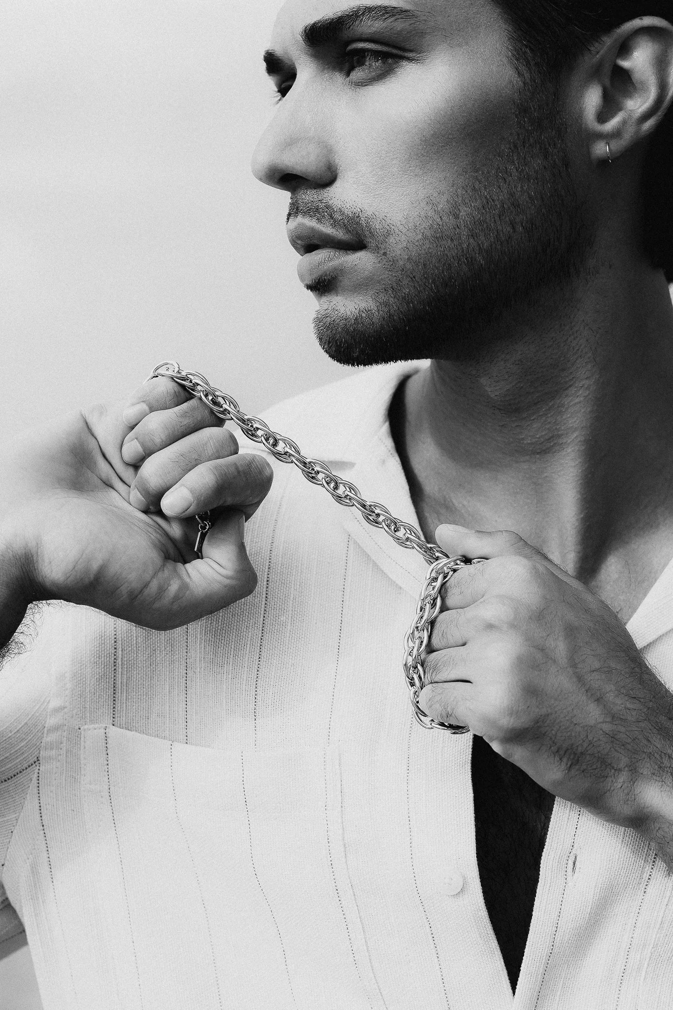 Photo de mode en noir et blanc d'un homme tenant un collier en or