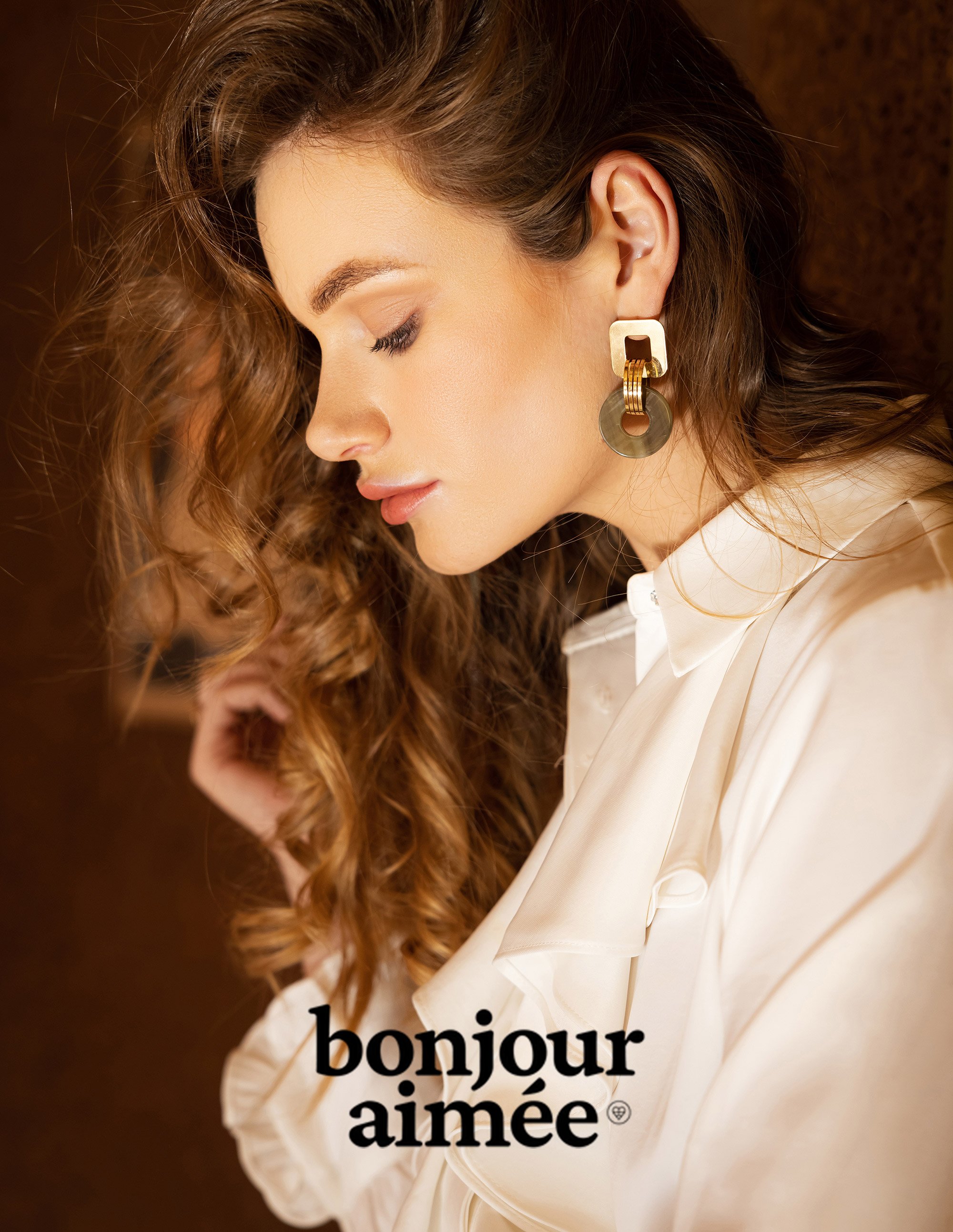 Mannequin aux cheveux bouclés portant des boucles d'oreilles en or