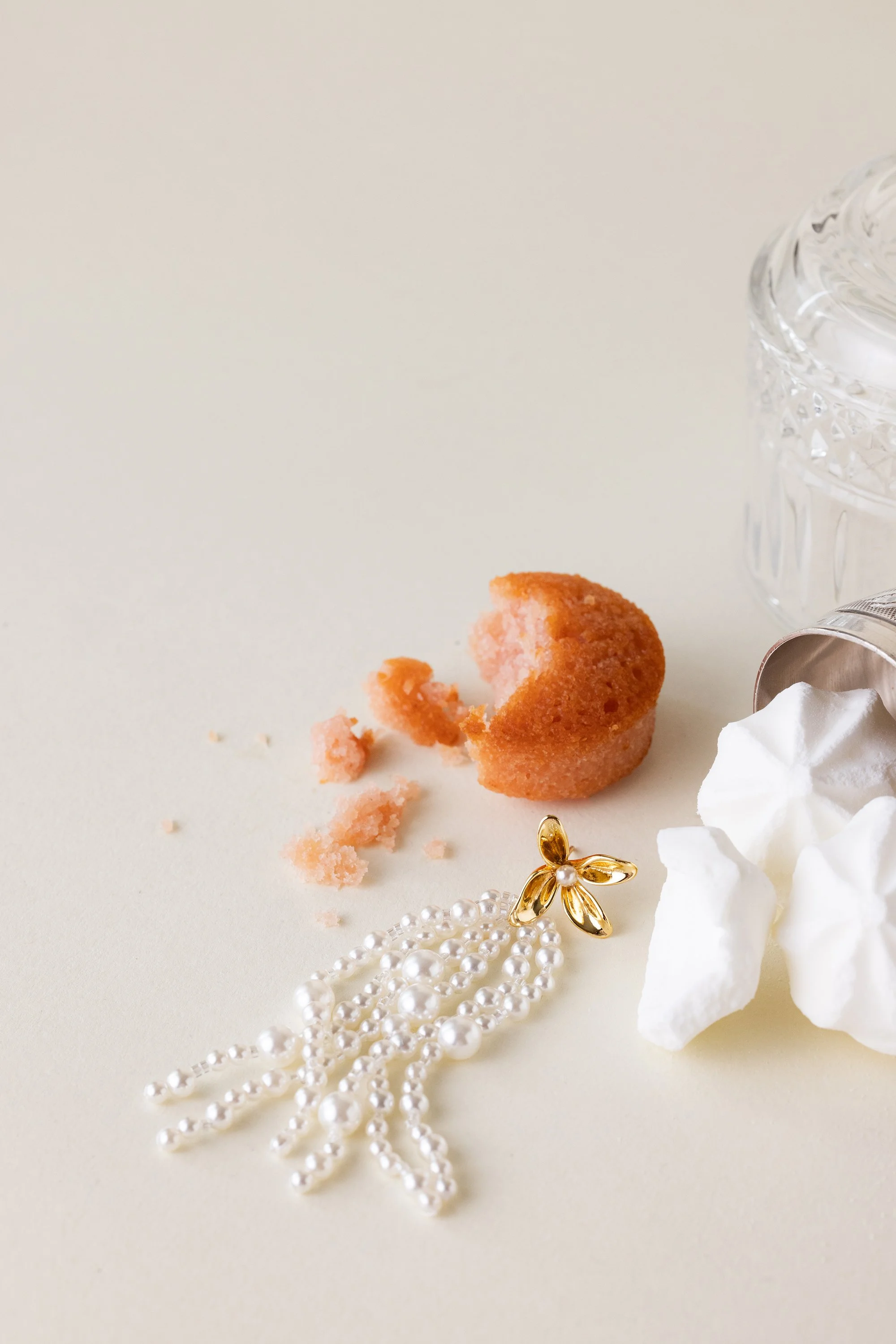 Nature morte d'une boucle d'oreille en perles posée à côté d'un gâteau et de meringues