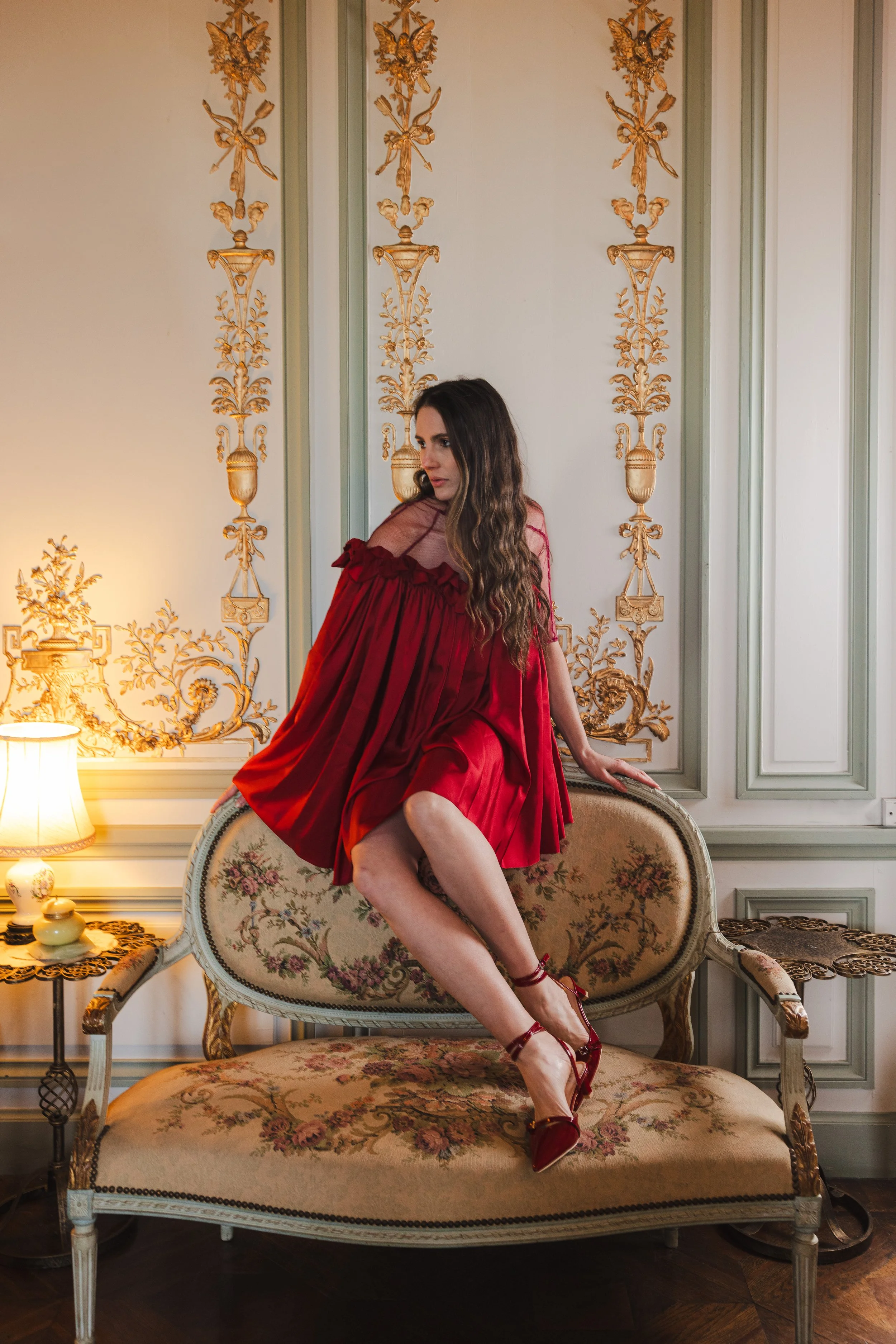 Mannequin portant une robe rouge en satin assise sur le dossier d'une banquette