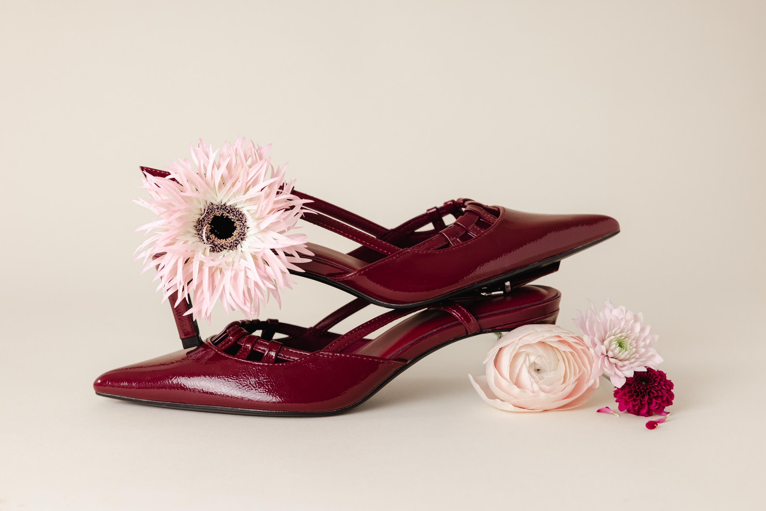 Composition de deux escarpins bordeaux entourés de fleurs roses