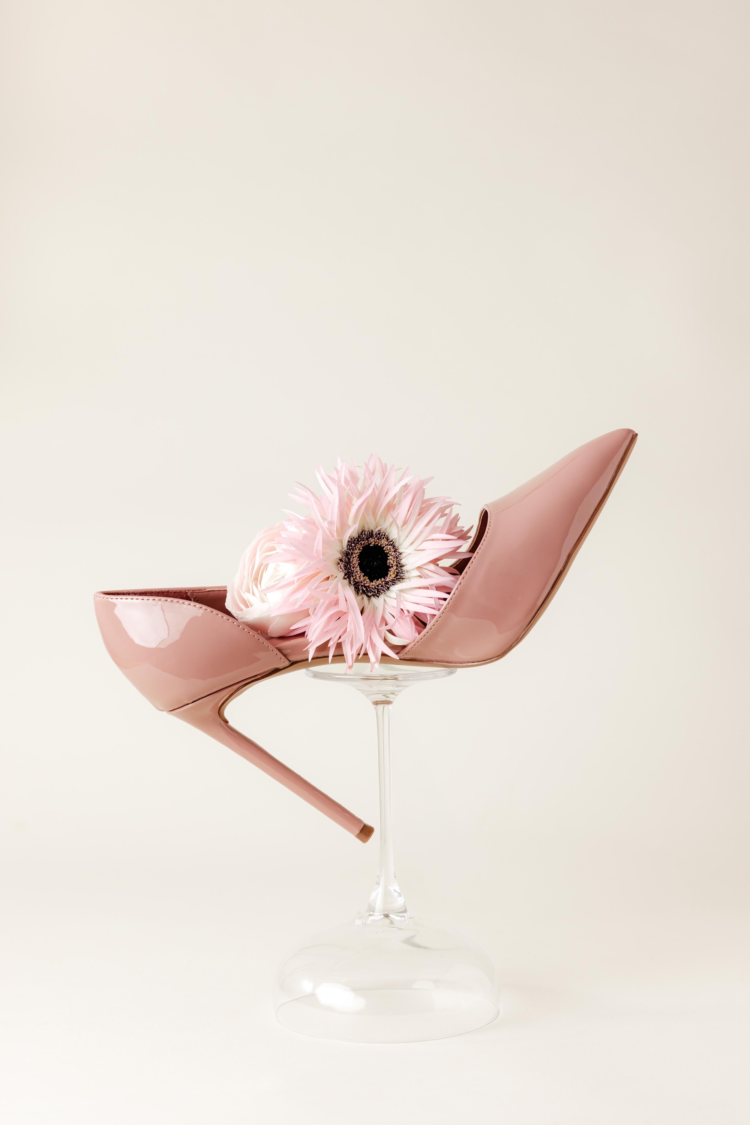 Nature morte d'un escarpin rose en équilibre sur un verre