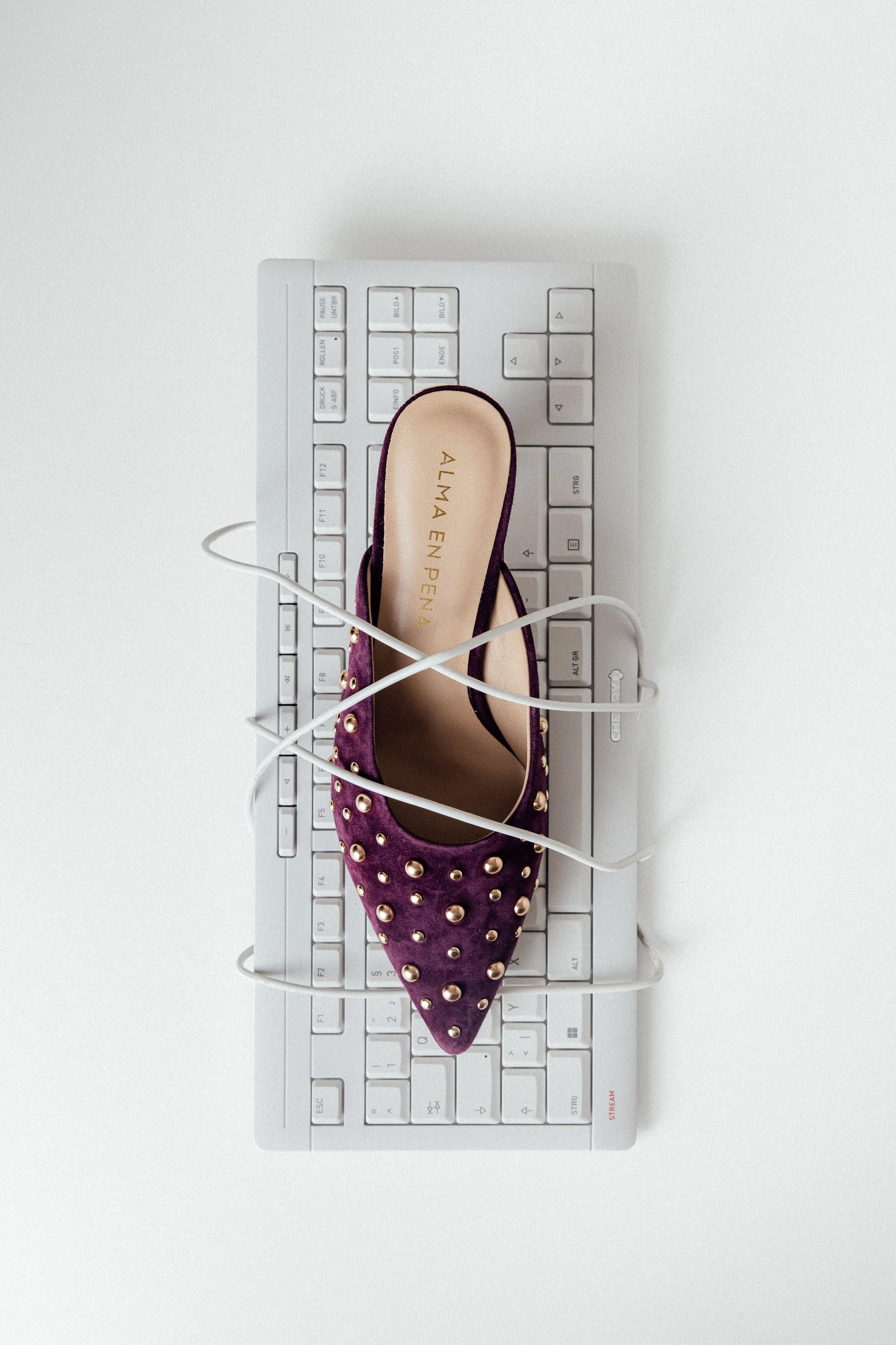Chaussures en velours posée sur un clavier d'ordinateur en studio sur fond blanc