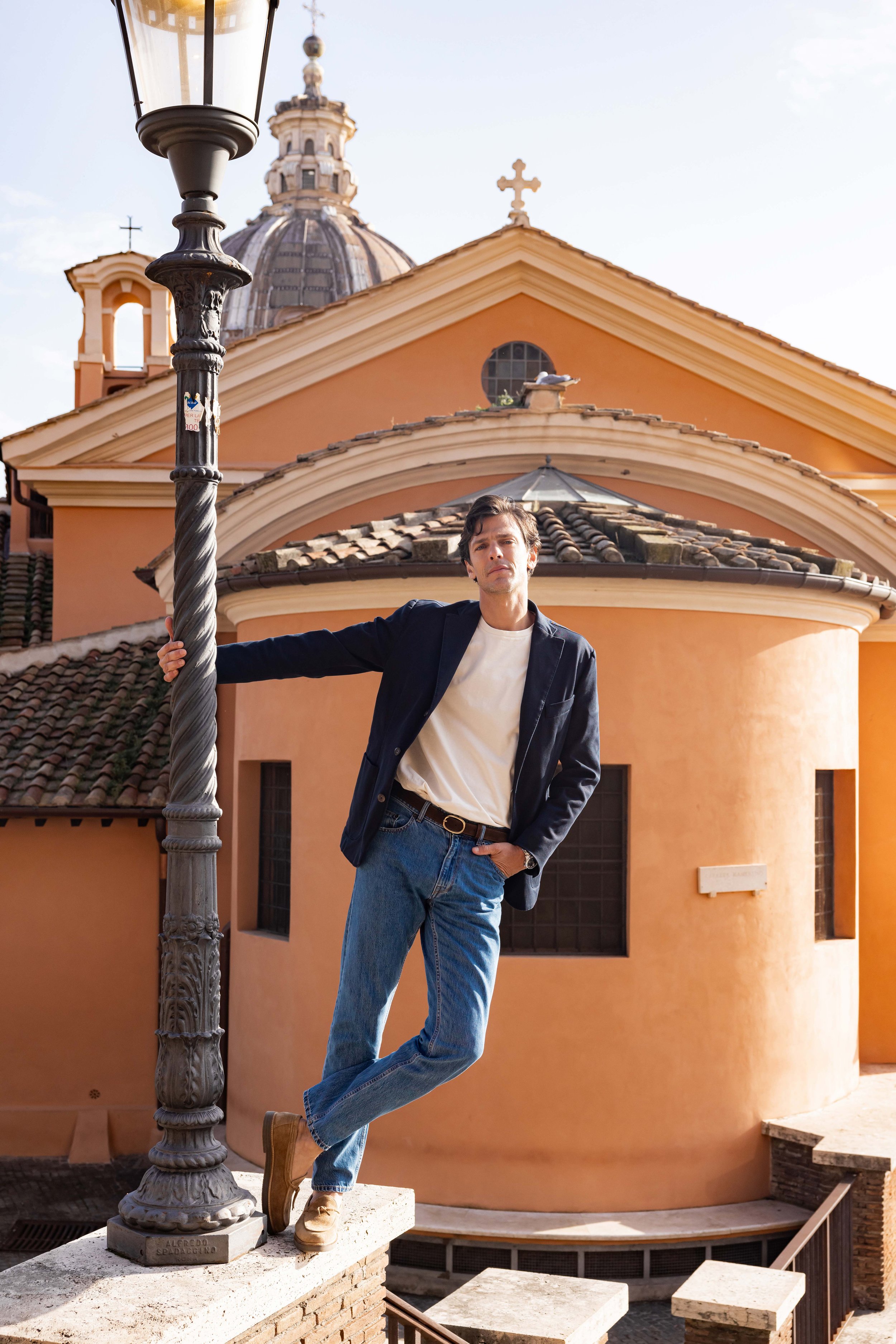 Homme posant debout et se tenant à un lampadaire dans une rue à Rome