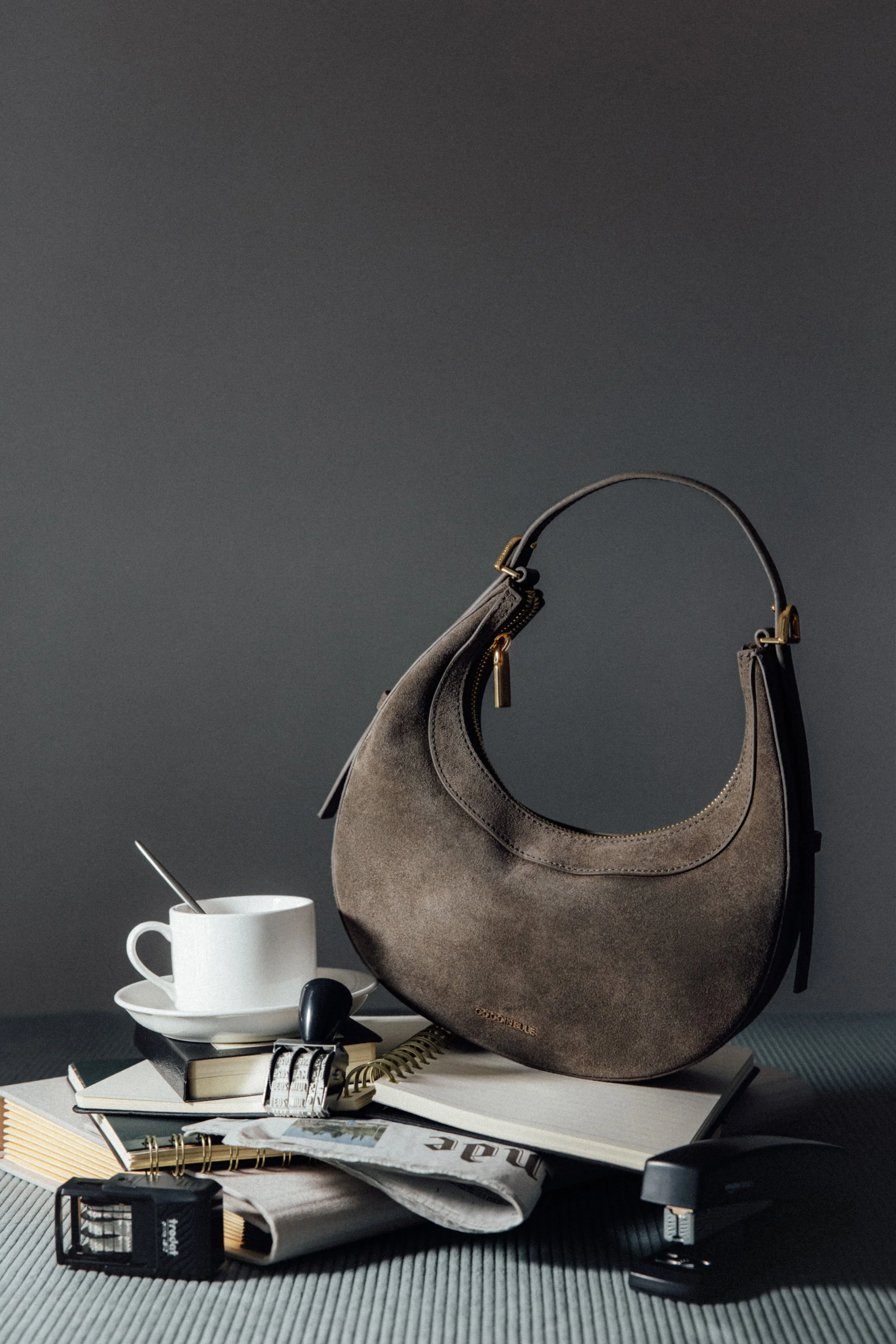 Scénographie d'un sac en cuir en studio posé sur un empilement d'accessoires de bureaux