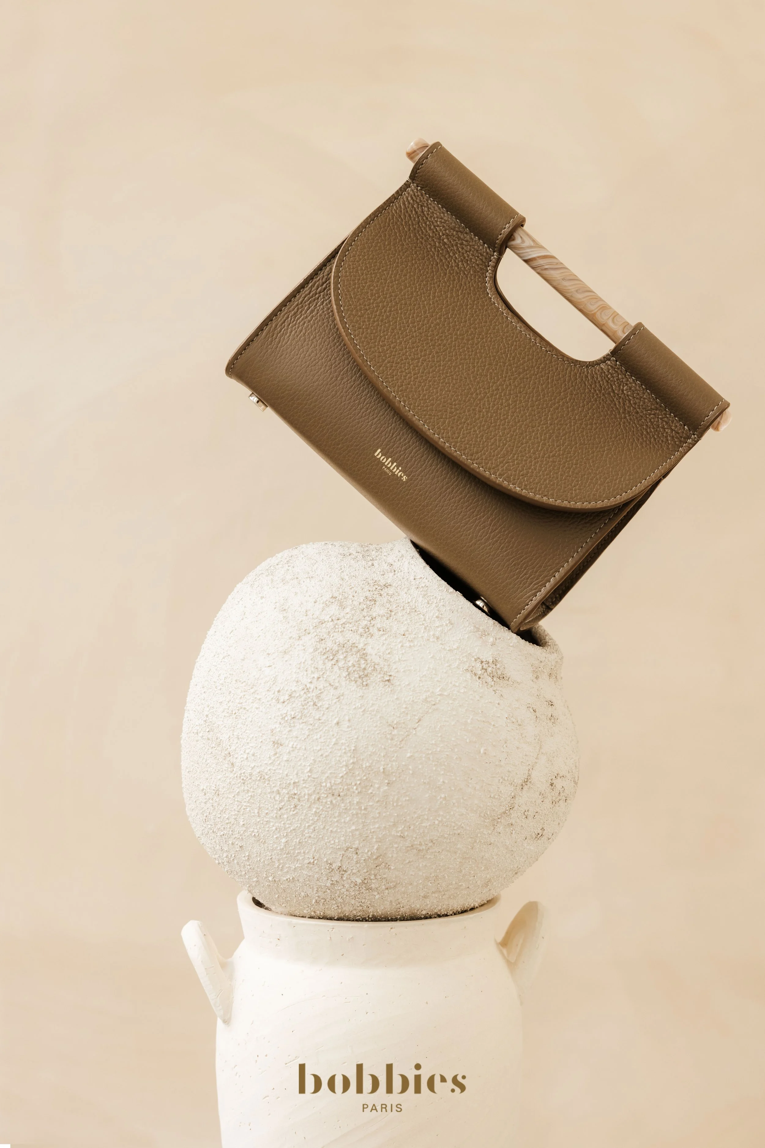 Sac en cuir posé en équilibre sur un empilement de vases