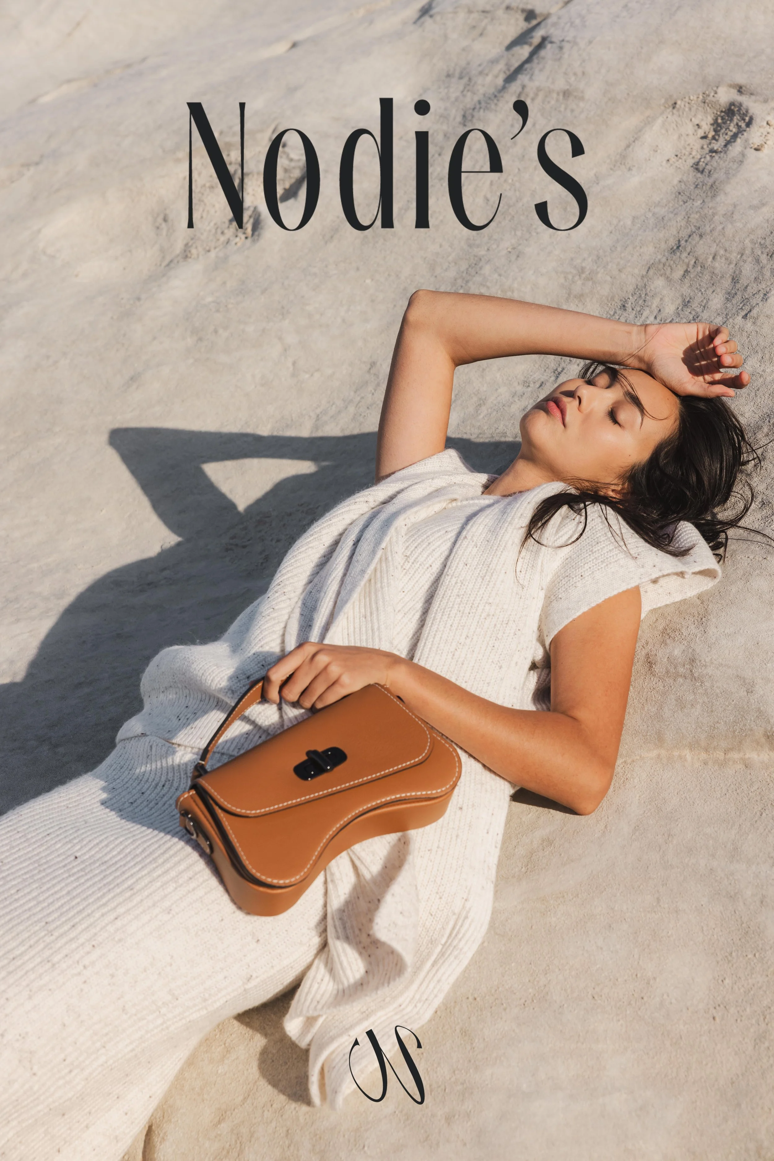 Mannequin allongée sur une plage à Milos et portant un sac en cuir