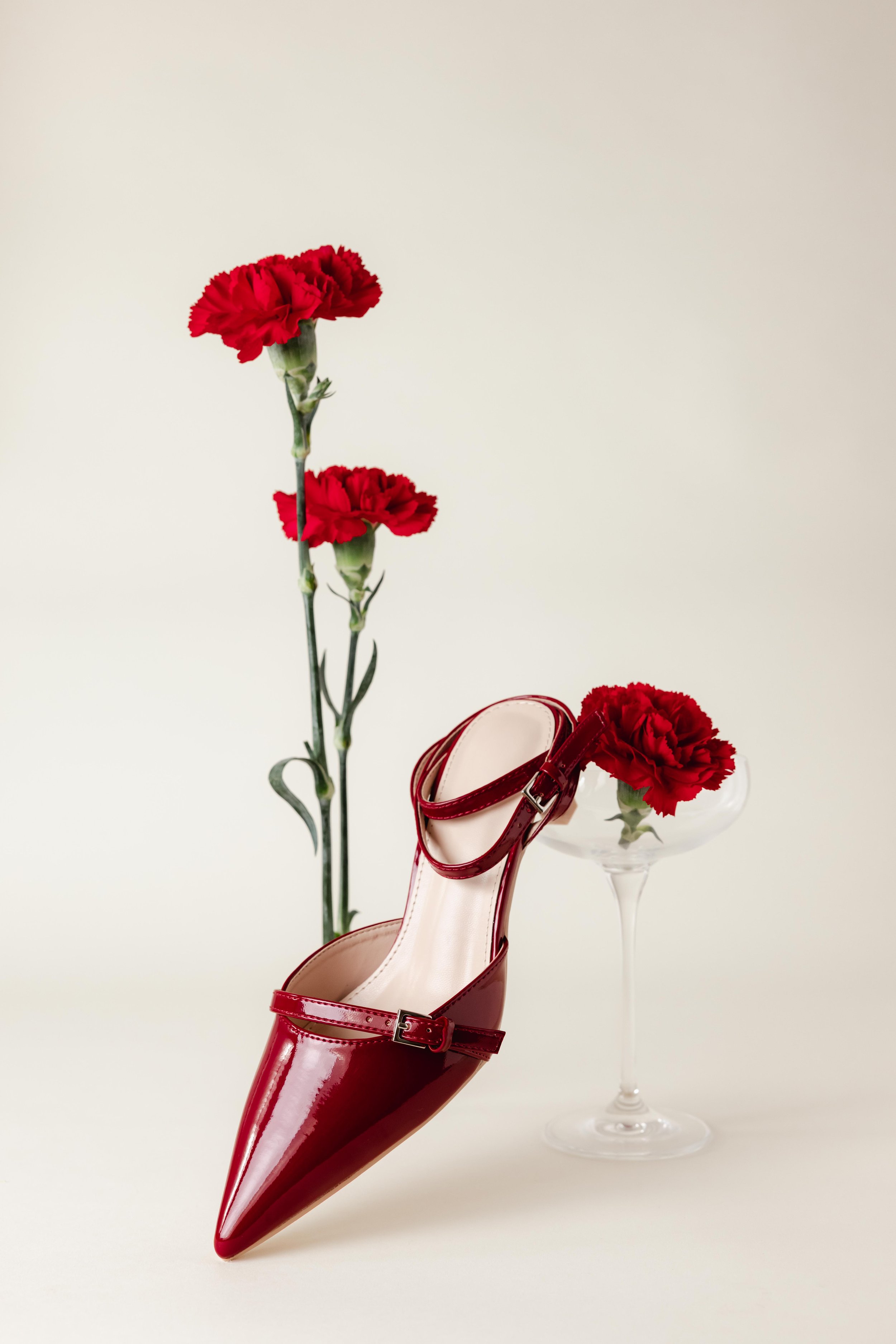 Chaussure rouge vernis en studio entourée de fleurs rouges