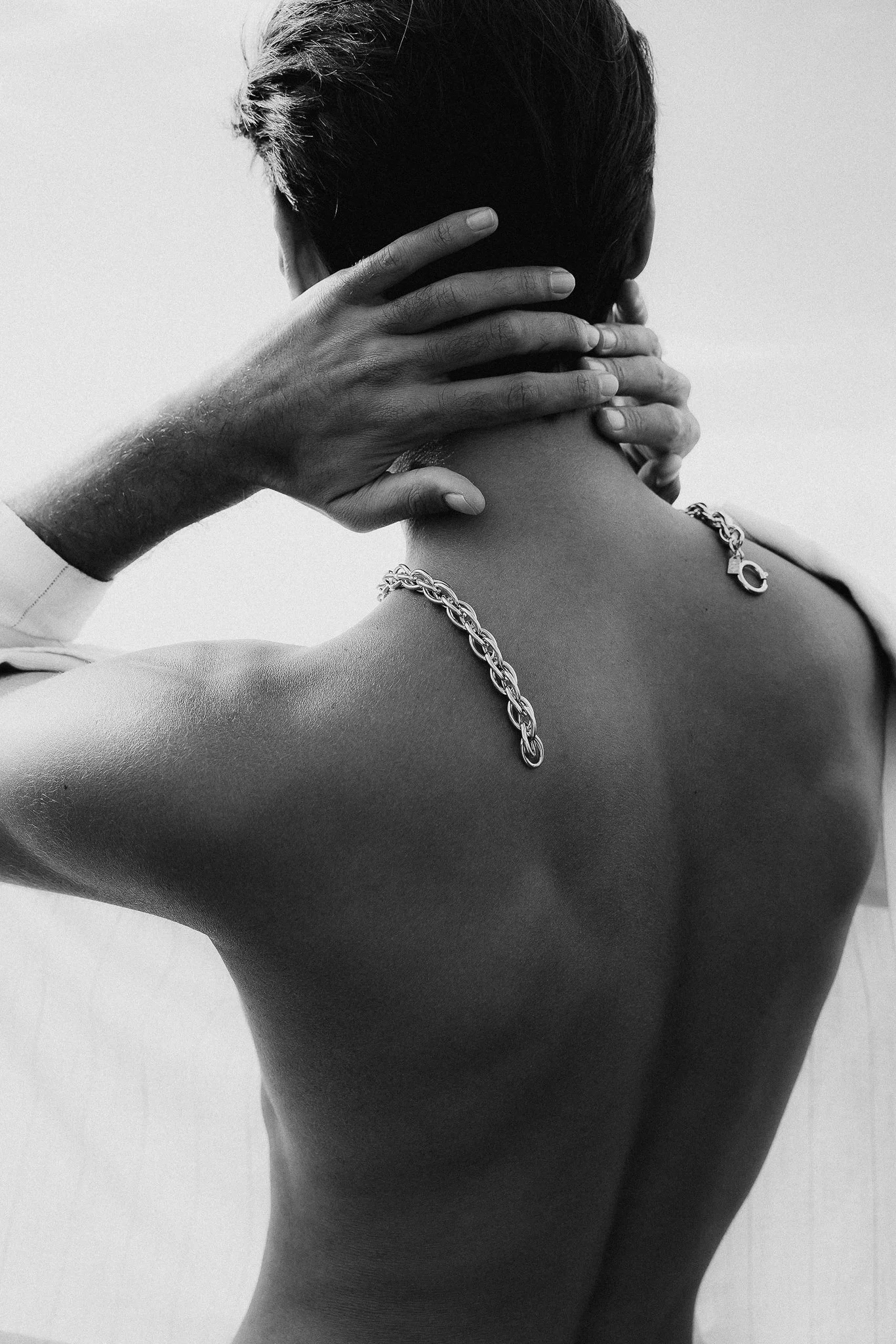 Photo de mode en noir et blanc d'un homme de dos portant un collier