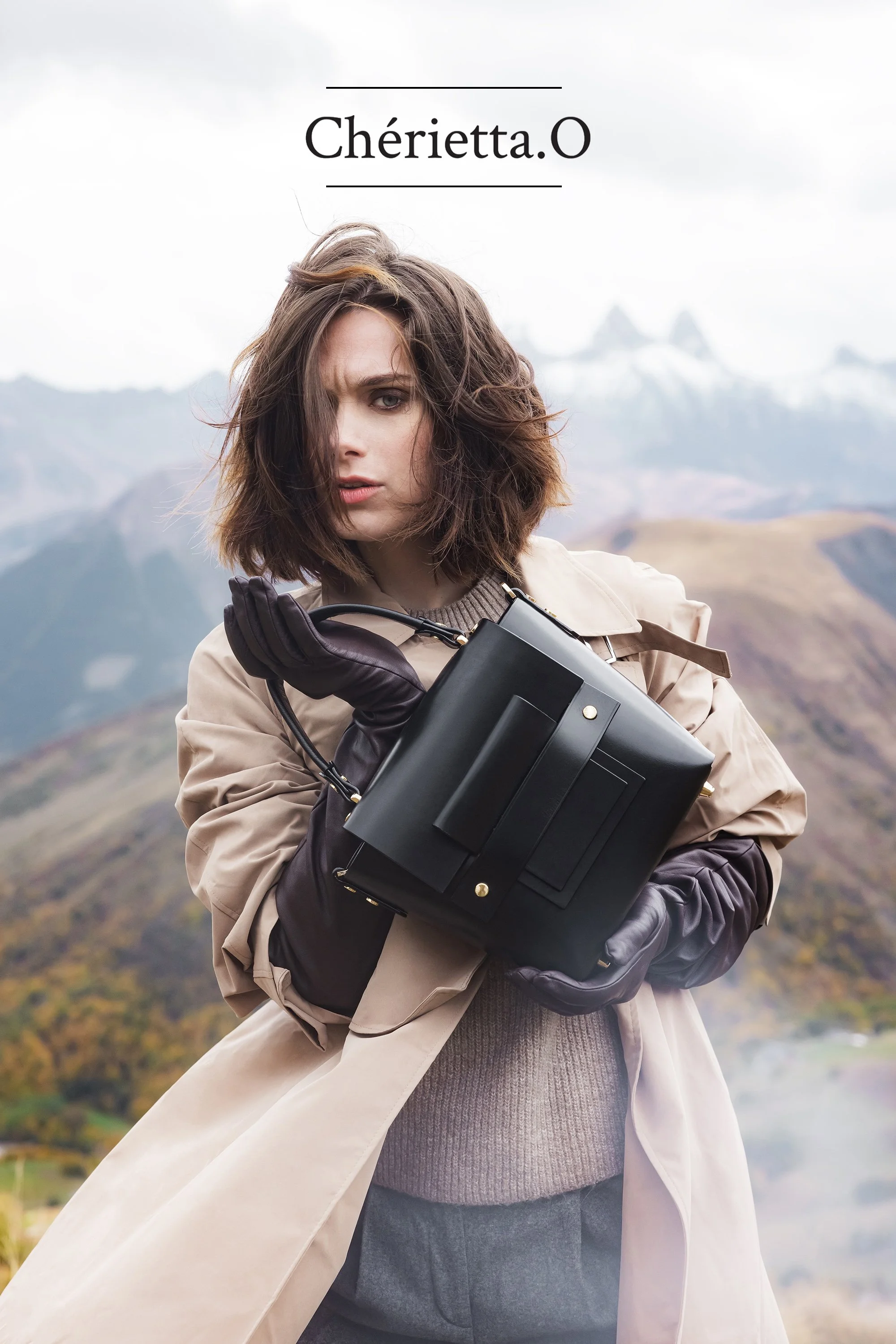 Mannequin en haut d'une montagne tenant un sac en cuir noir