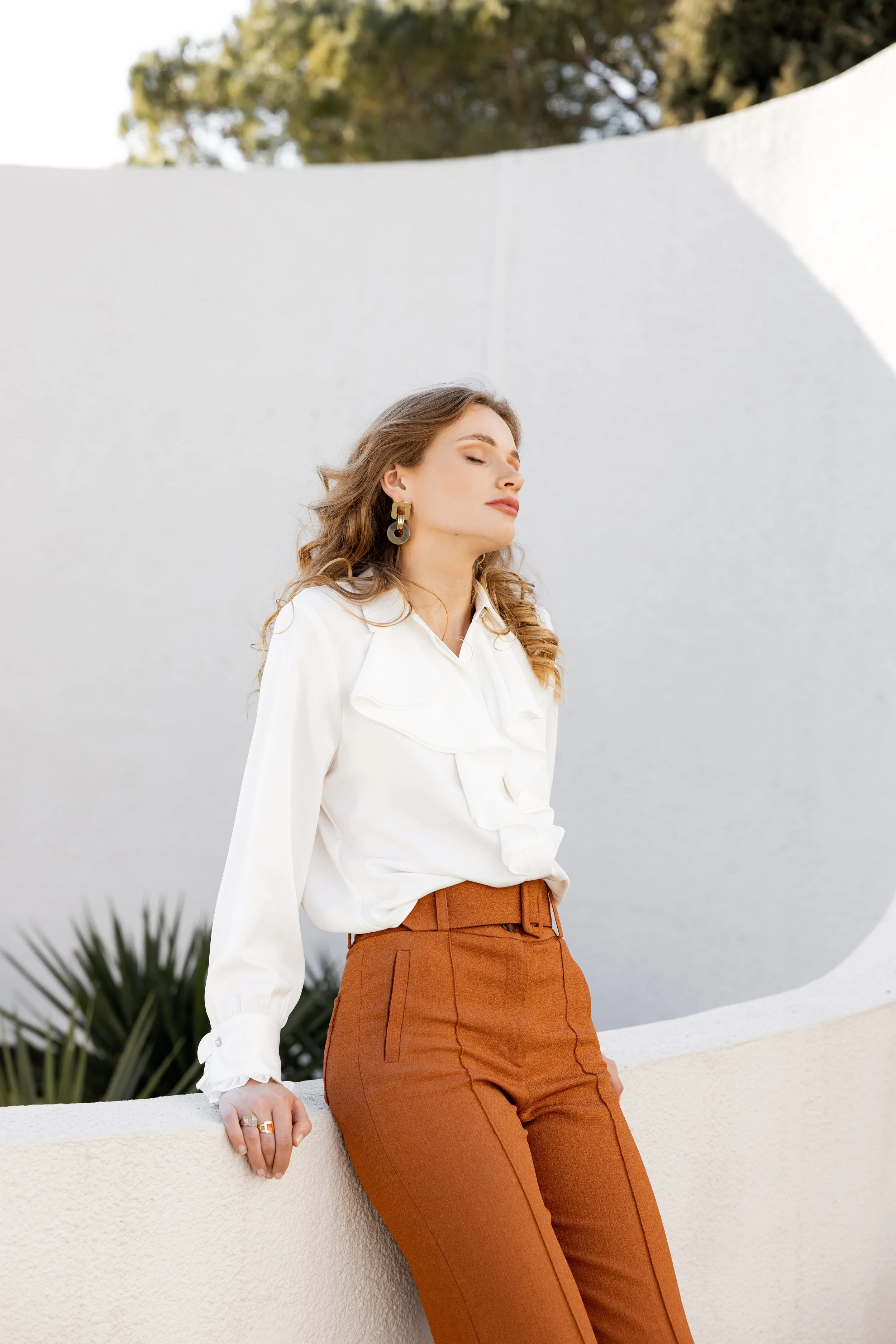 Portrait d'une mannequin portant un chemisier blanc et un pantalon Sézane orange