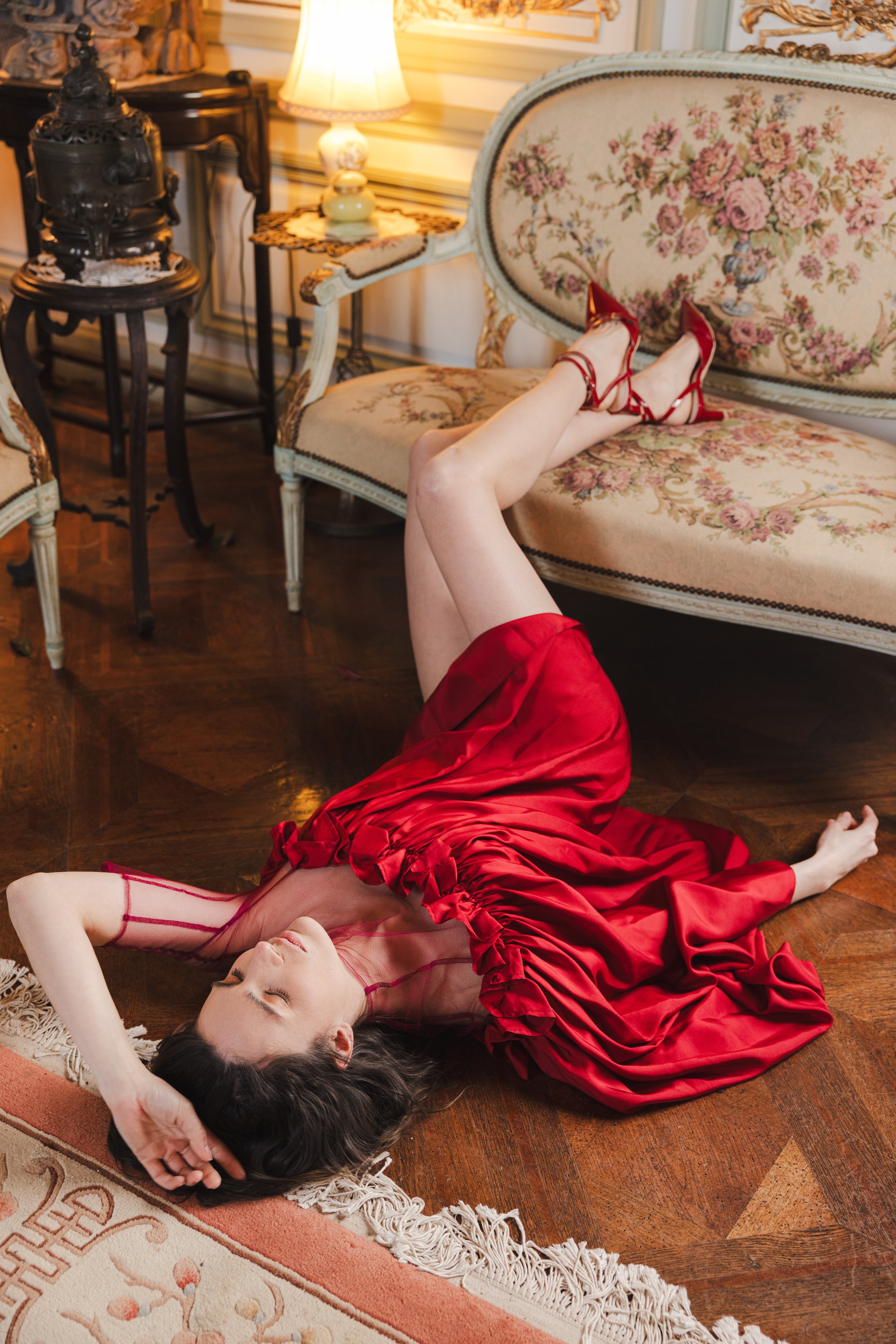 Mannequin posant allongée sur le parquet ancien d'un château dans une robe rouge
