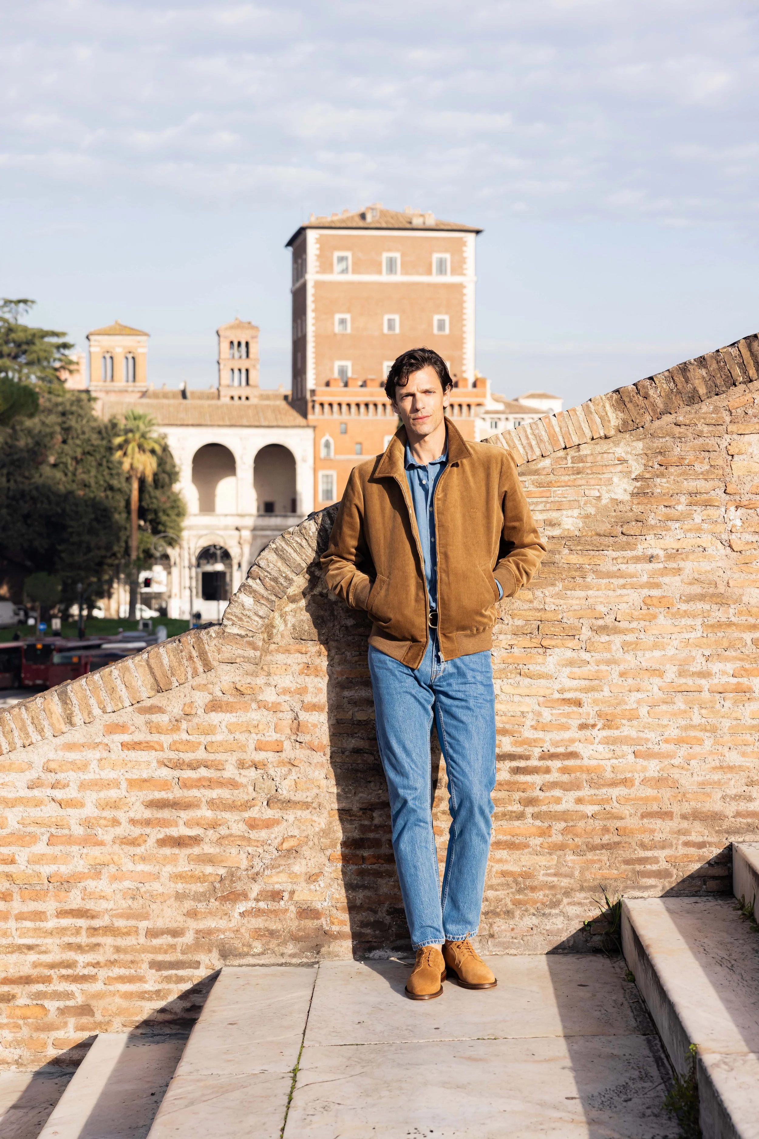 Mannequin homme posant debout dans des escaliers en pierre sous un ciel bleu