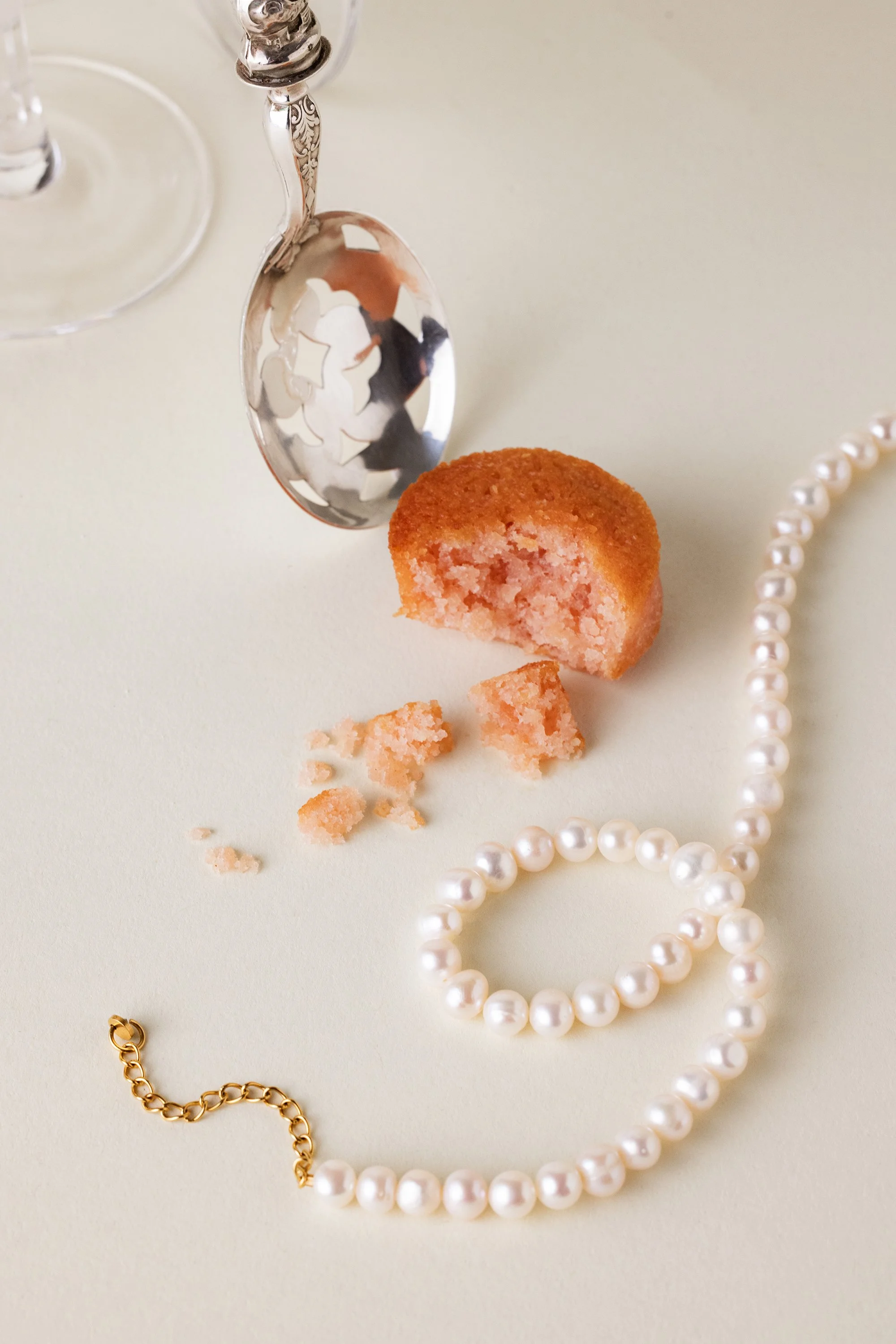 Nature morte délicate d'un collier en perles posé à côté d'un gâteau et d'une cuillère en argent