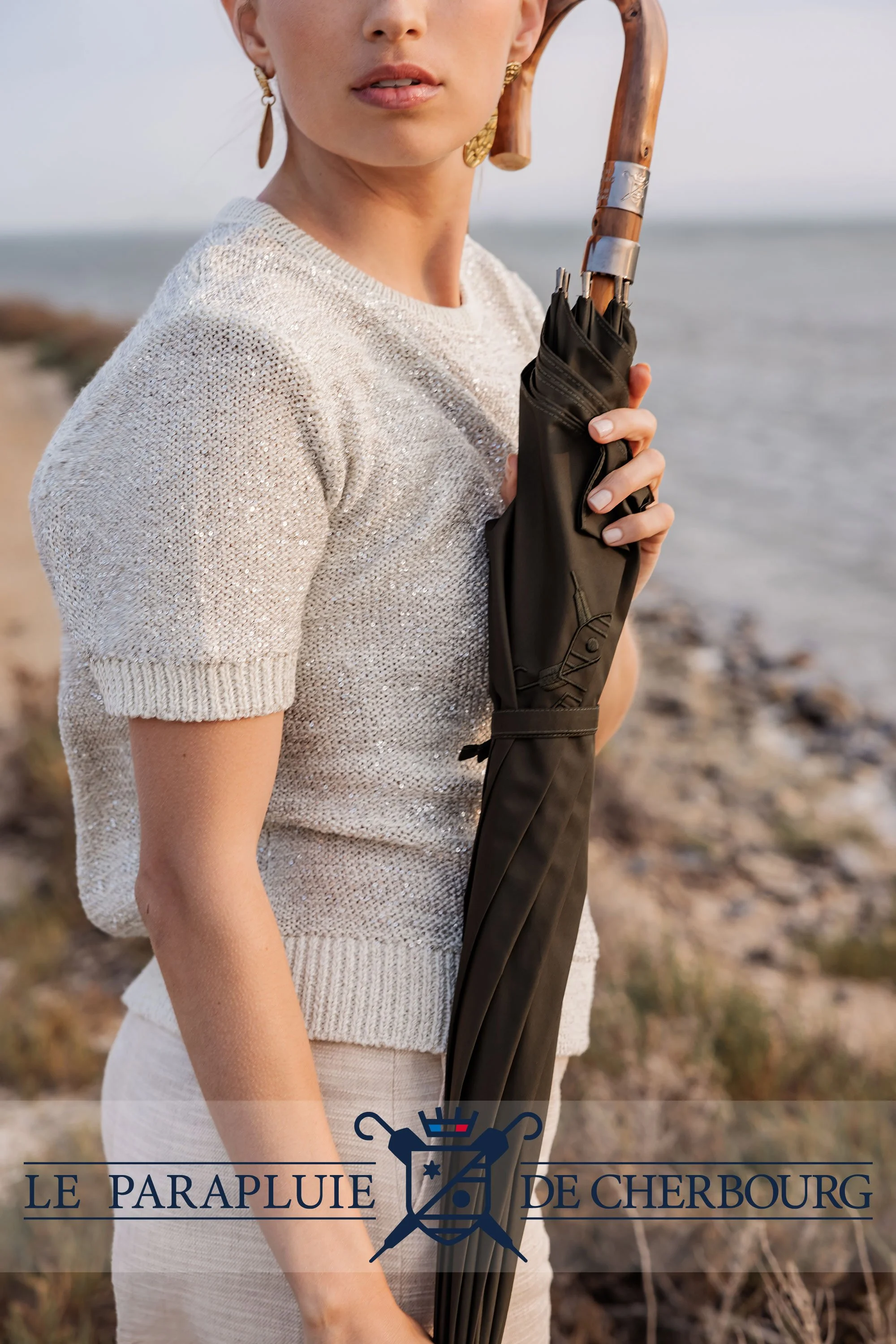 Femme tenant un parapluie avec la mer en fond