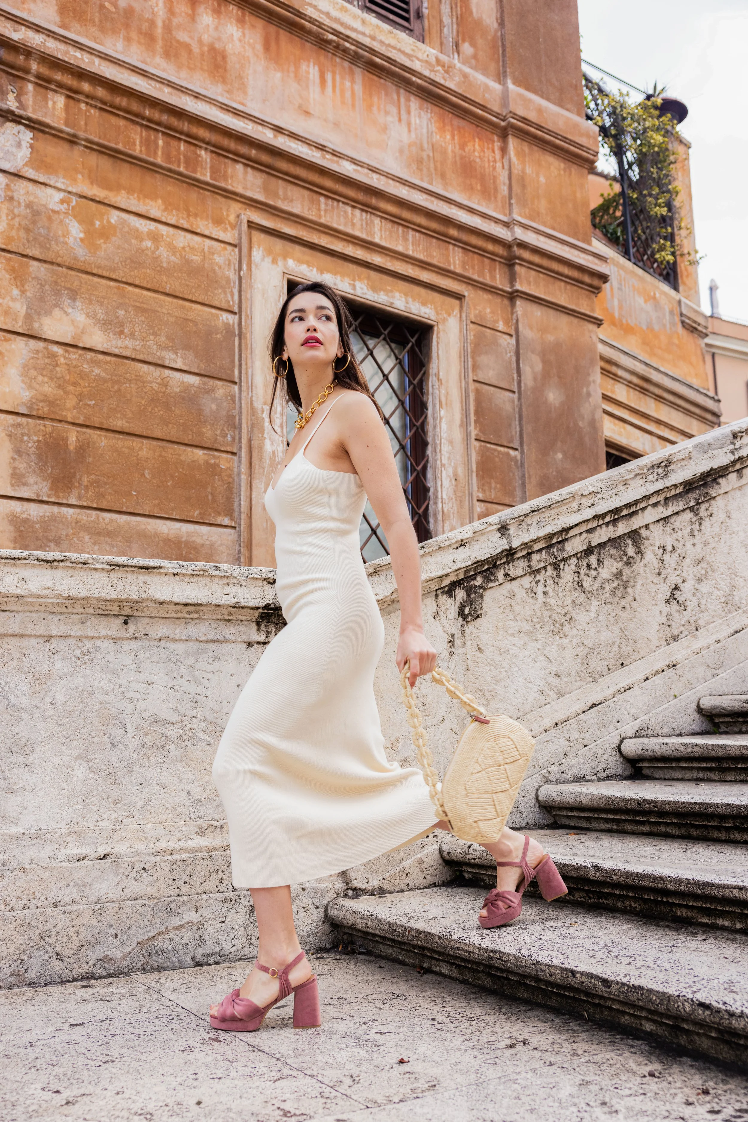 Mannequin portant une robe ivoire et posant dans des escaliers en pierre à Rome
