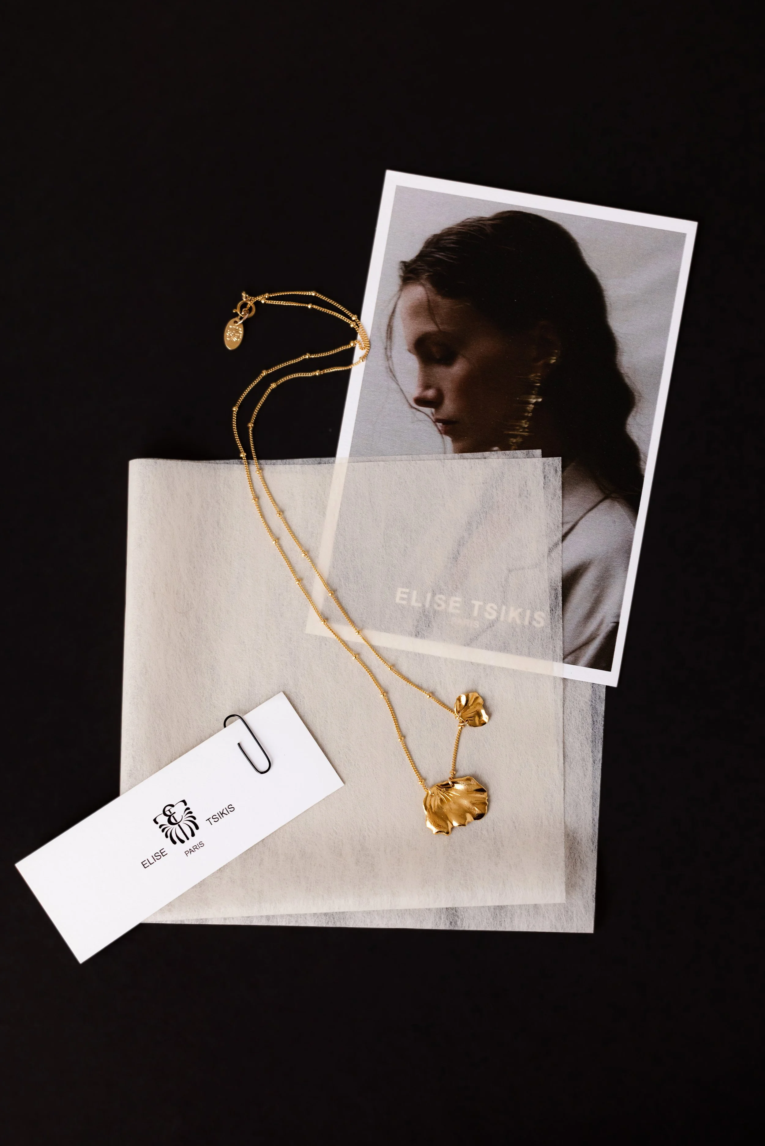 Ensemble de cartes accompagnées d'un collier en or posés sur fond noir