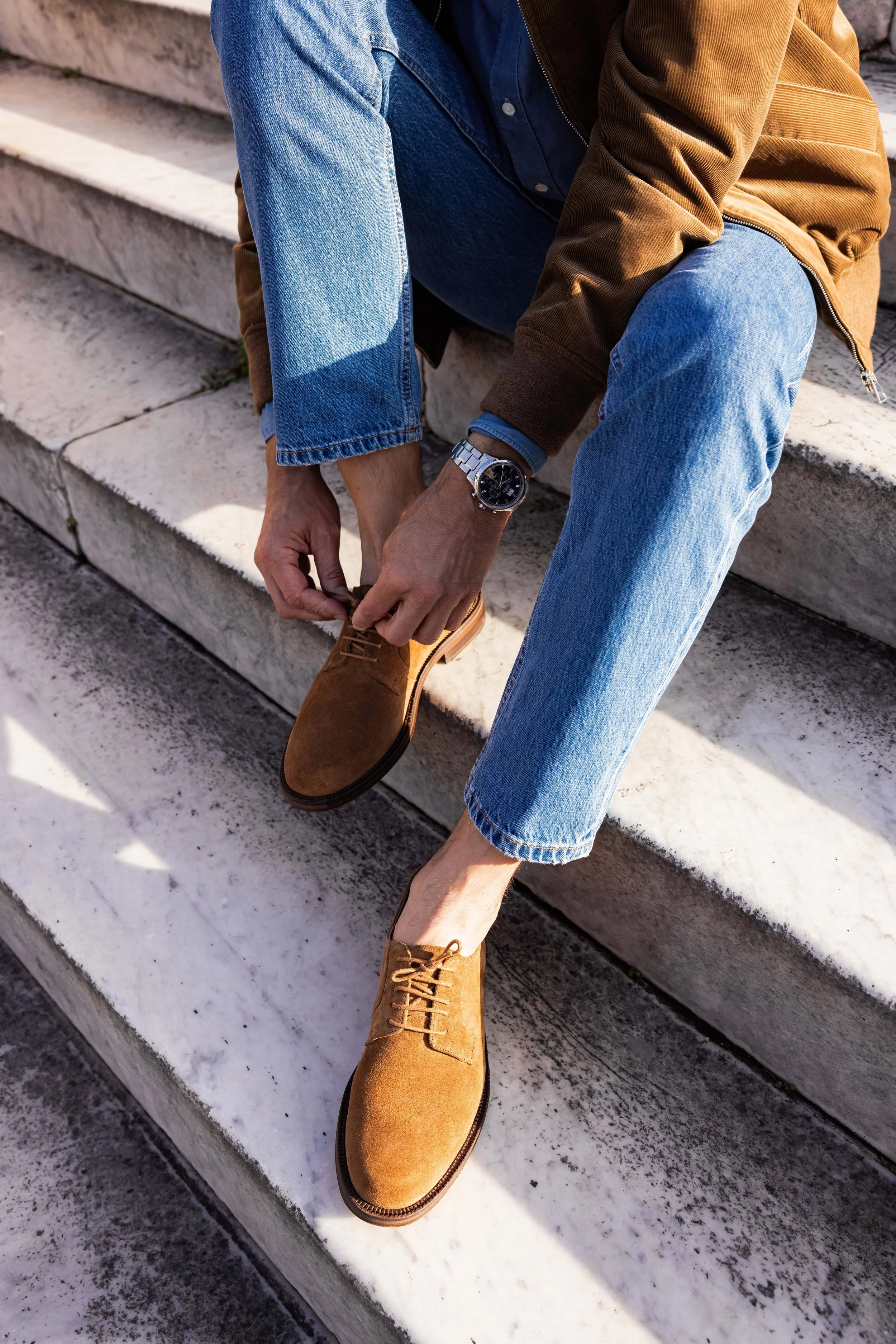 Paire de mocassins portée par un mannequin homme assis dans des escaliers en pierre