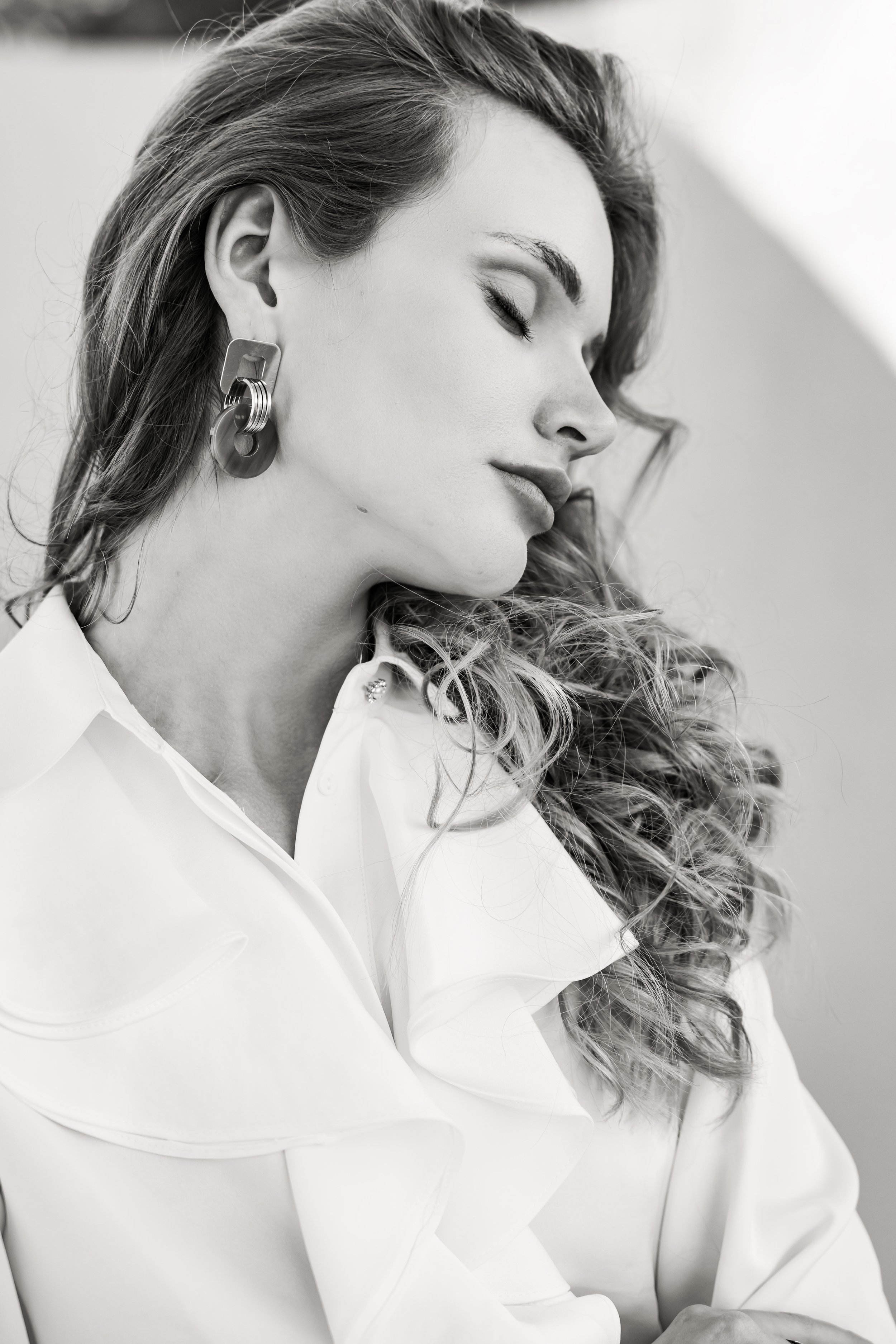 Portrait en noir et blanc d'une mannequin la tête penchée pour montrer sa boucle d'oreille