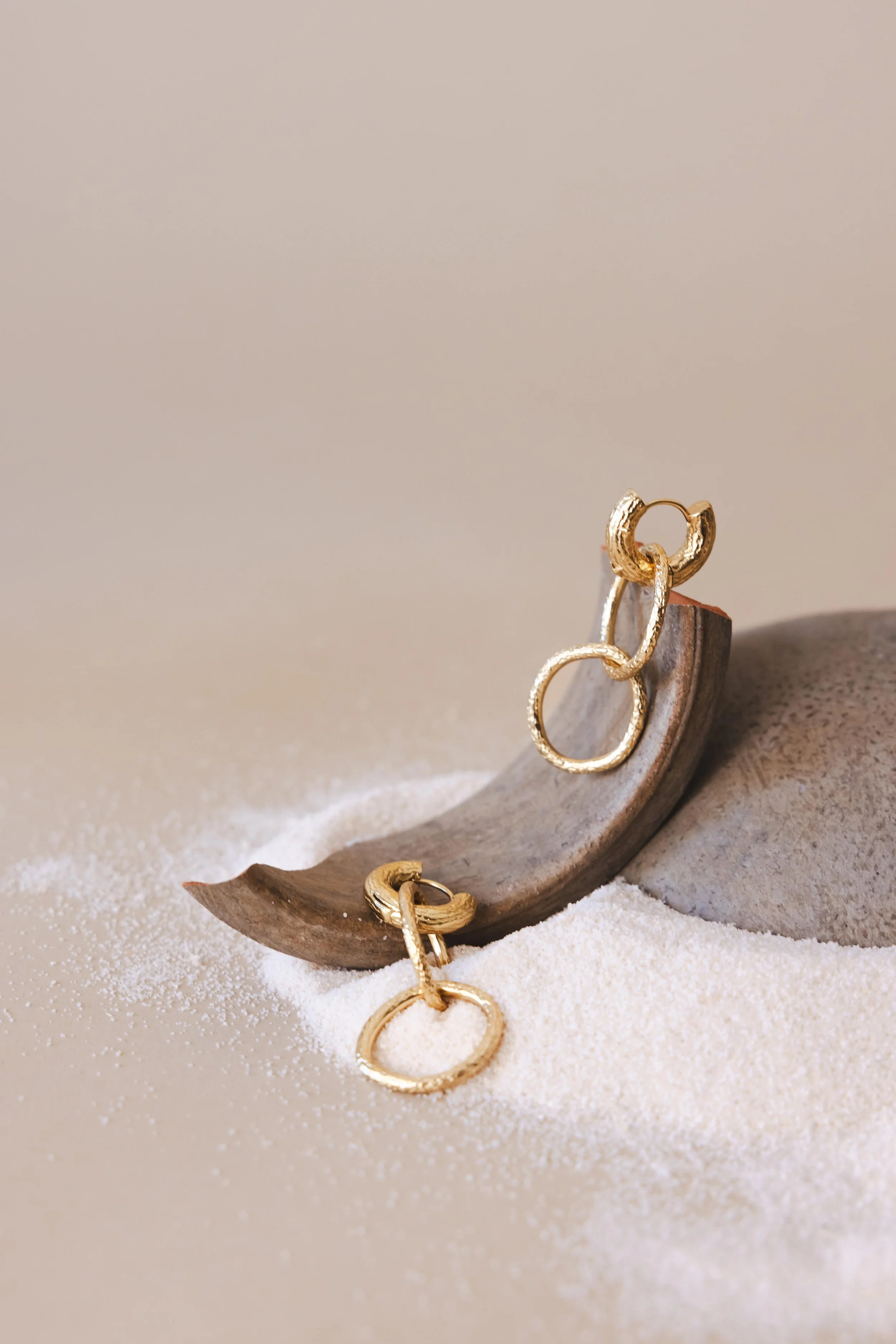 Nature morte de boucles d'oreilles en or posées sur un morceau de céramique