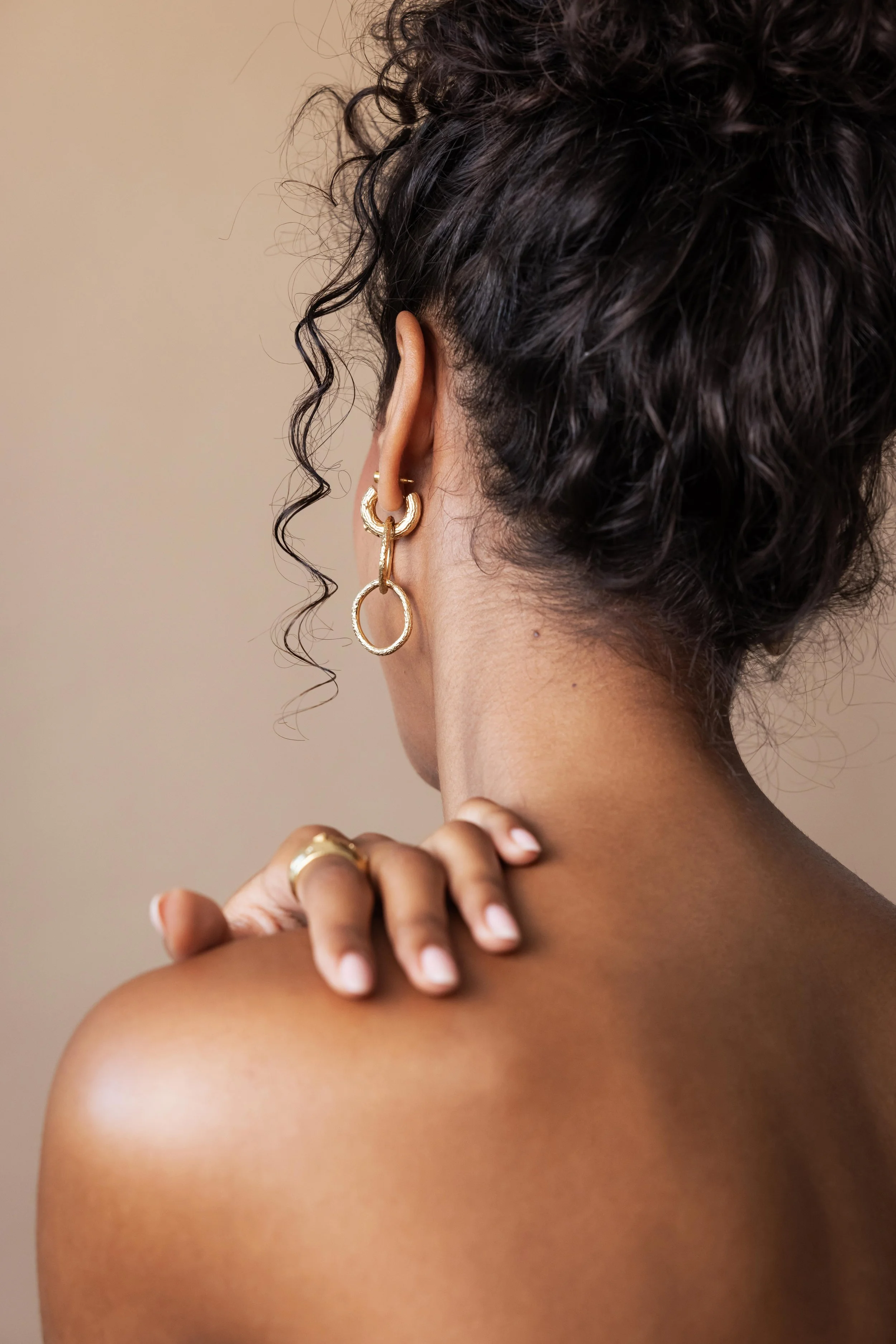 Main d'une mannequin posée sur son épaule orné d'une bague en or