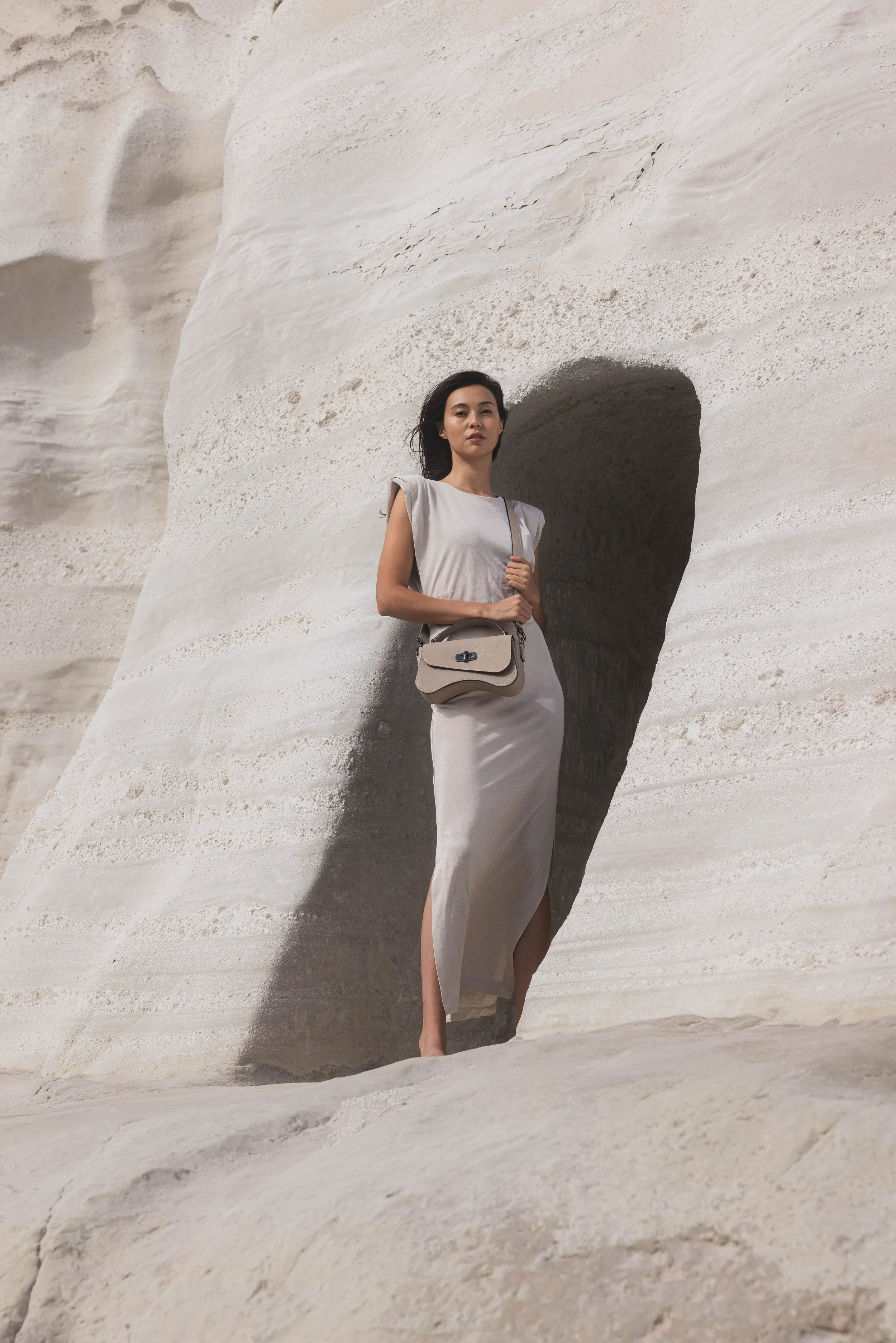 Mannequin se tenant debout à l'entrée d'une grotte toute en roche minérale blanche et portant une robe assortie