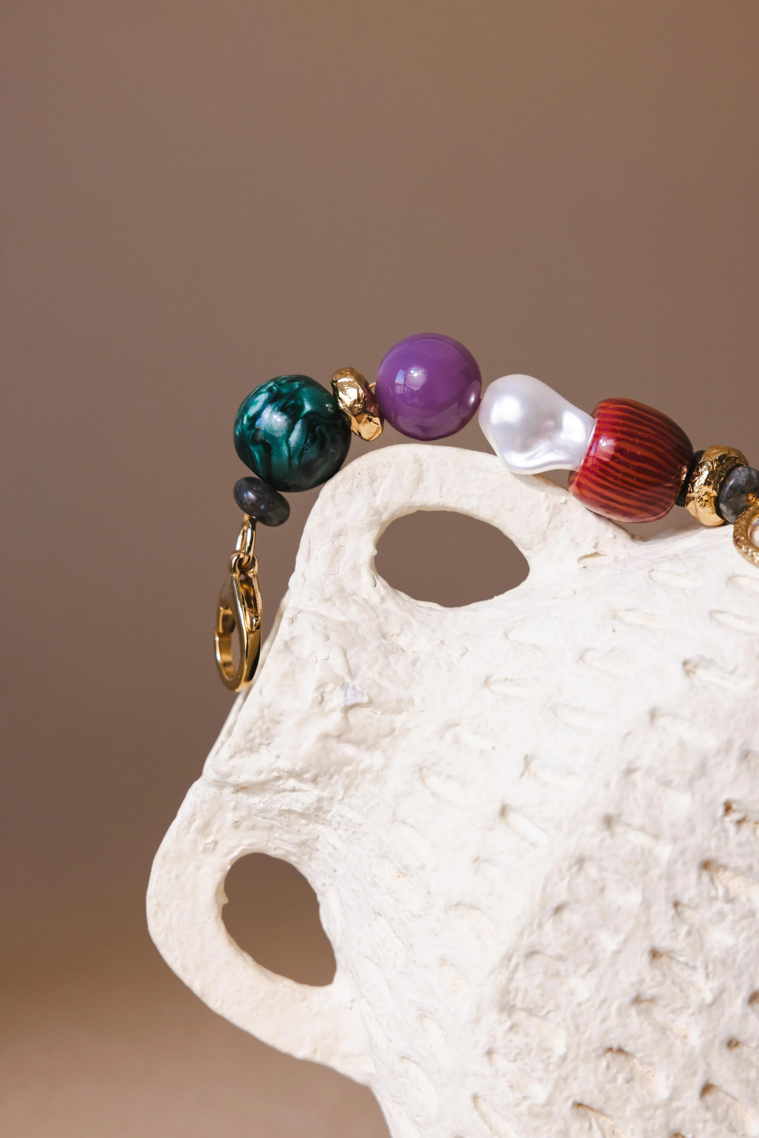 Nature morte d'un colliers en grosses perles colorées posé sur un vase