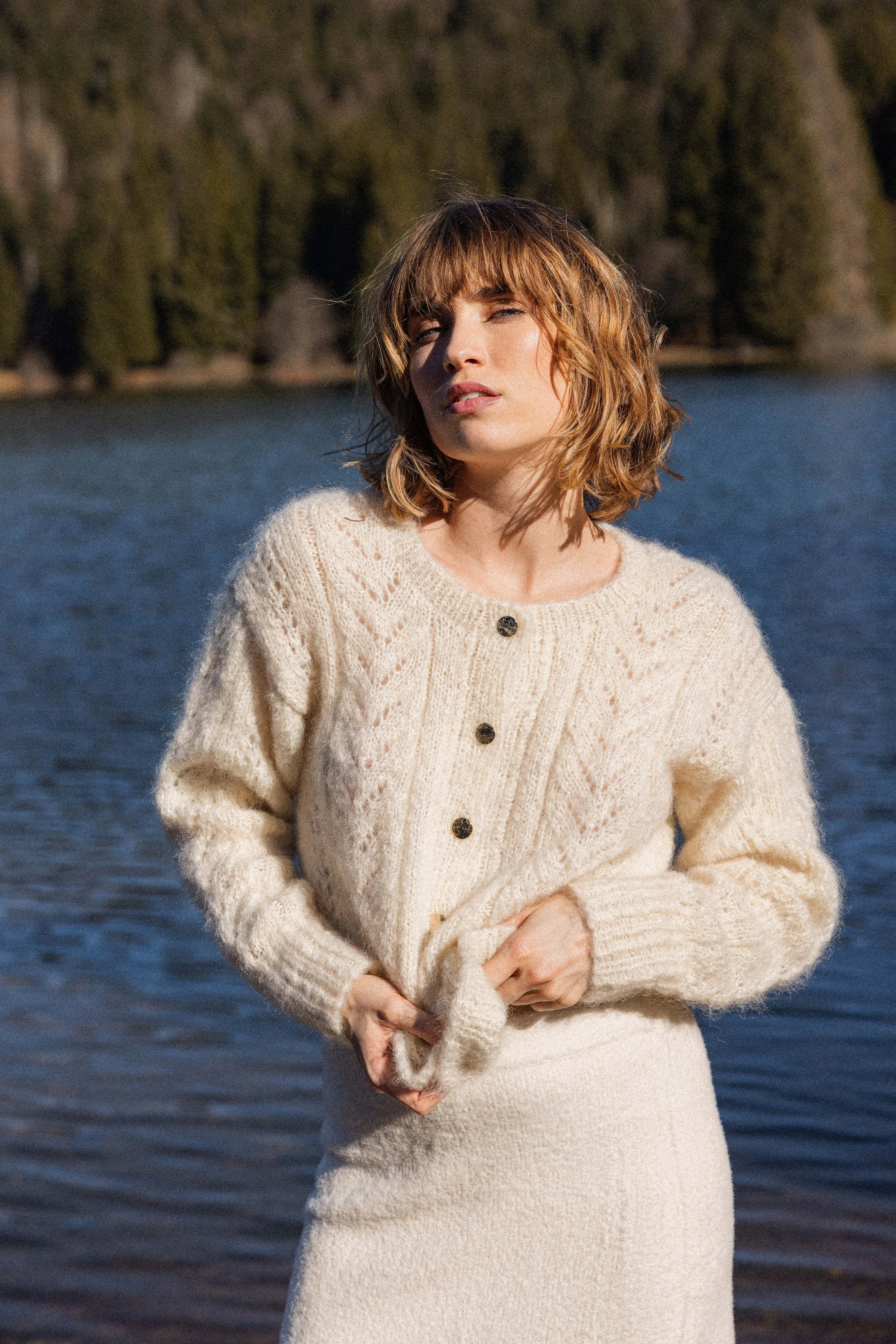 Mannequin portant un pull en laine se tenant face à un lac
