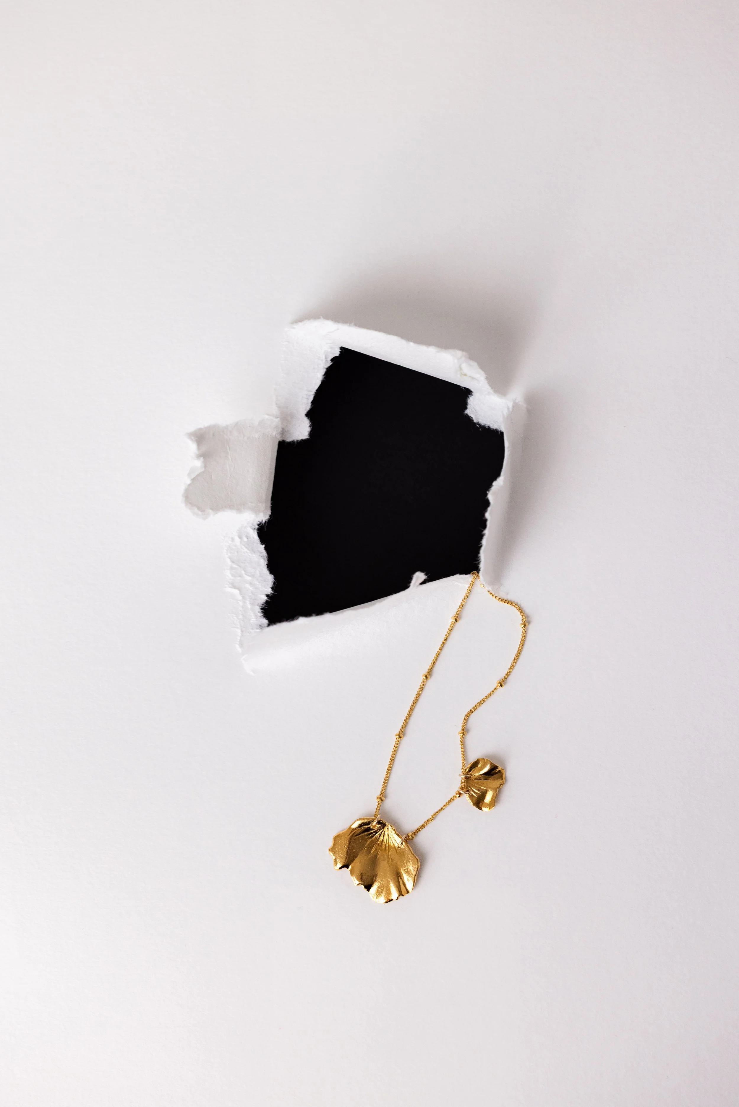 Collier en or posé sur une feuille blanche déhirée