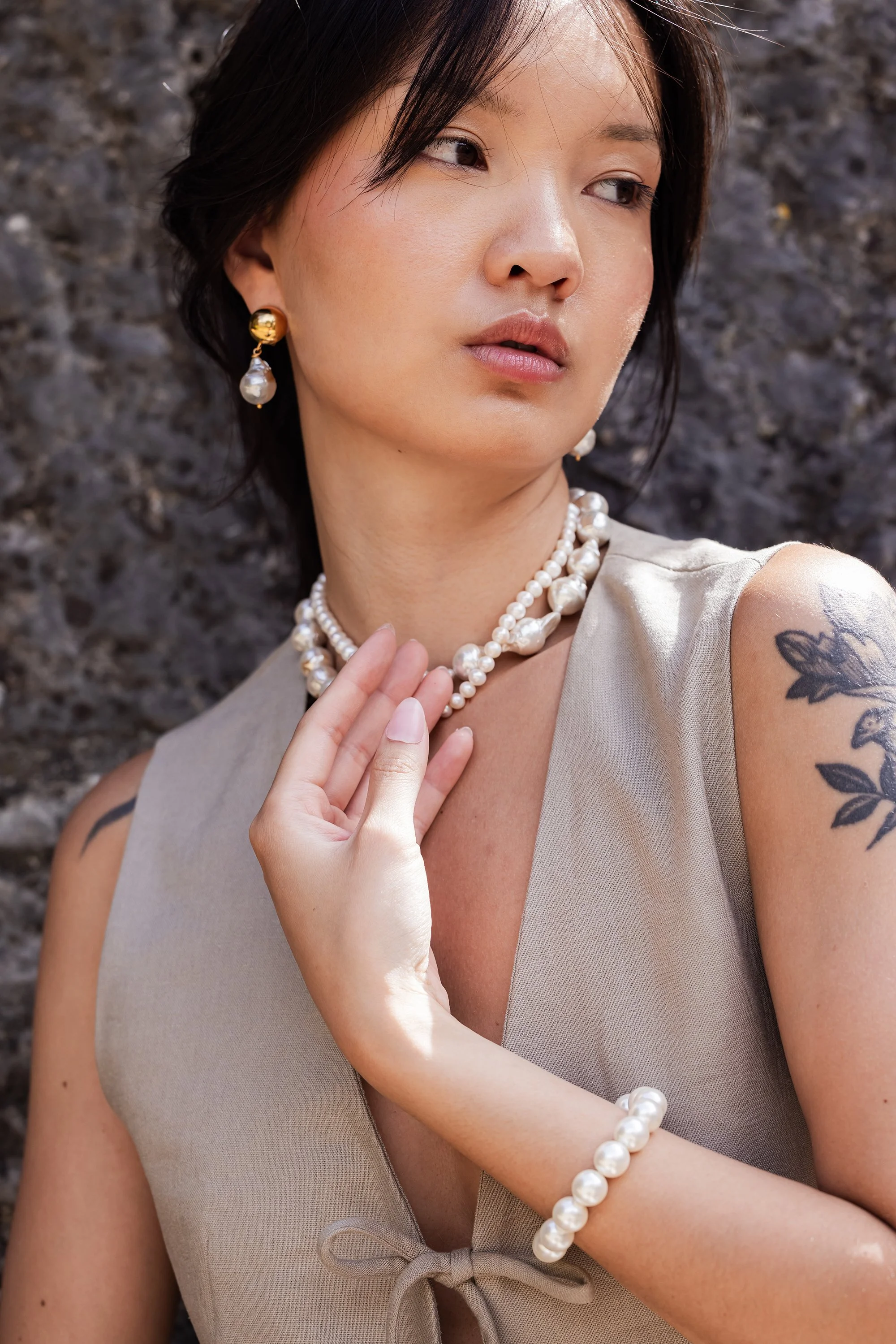 Portrait d'une mannequin portant un top en lin sans manche et une parure de bijoux en perles