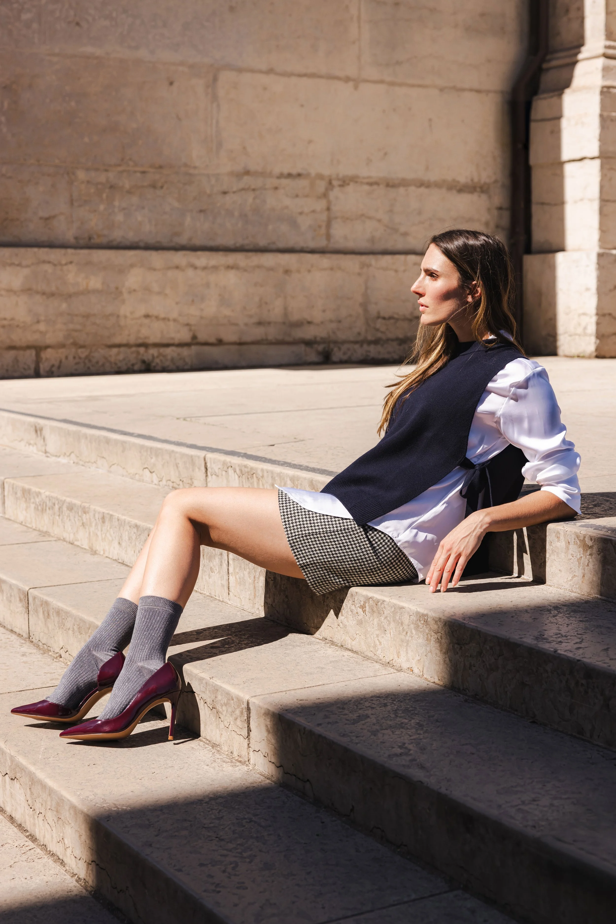 Femme assise dans des escaliers en pierre en extérieur sous une lumière solaire