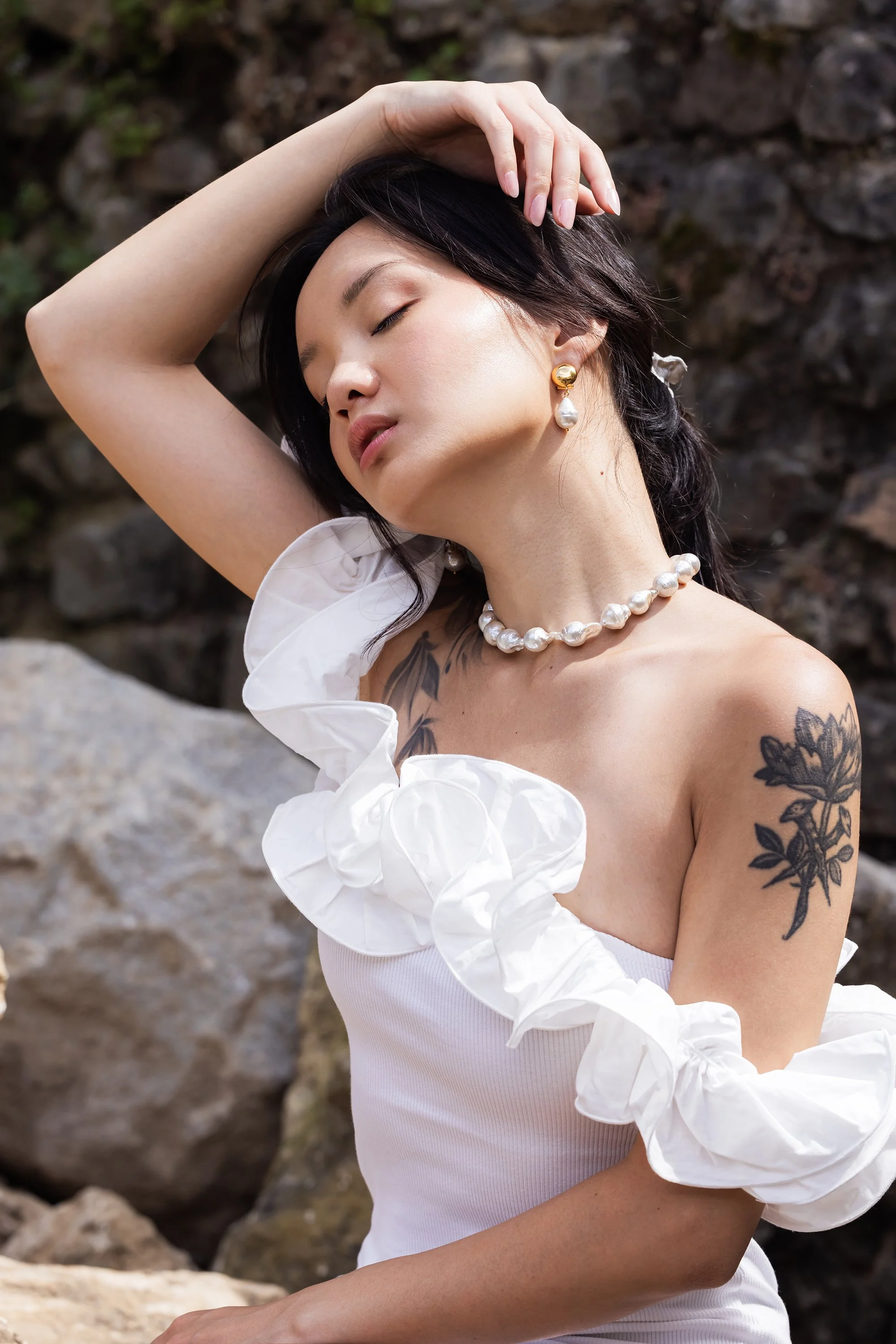 Portrait délicat d'une mannequin en robe blanche et portant un collier et des boucles en perles