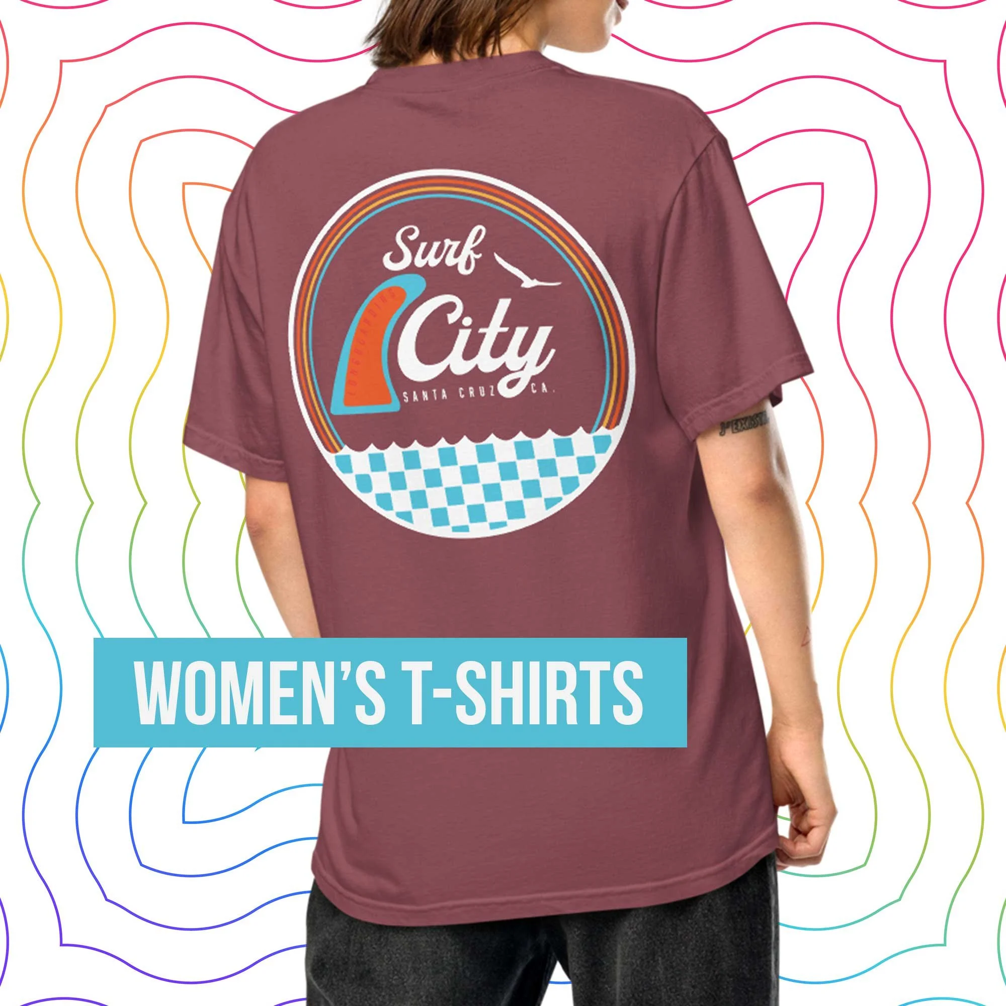 Back view of a woman wearing a maroon Surf City Santa Cruz T-shirt with a retro surf graphic, shown against a colorful wavy background with a blue label reading “Women’s T-Shirts.”