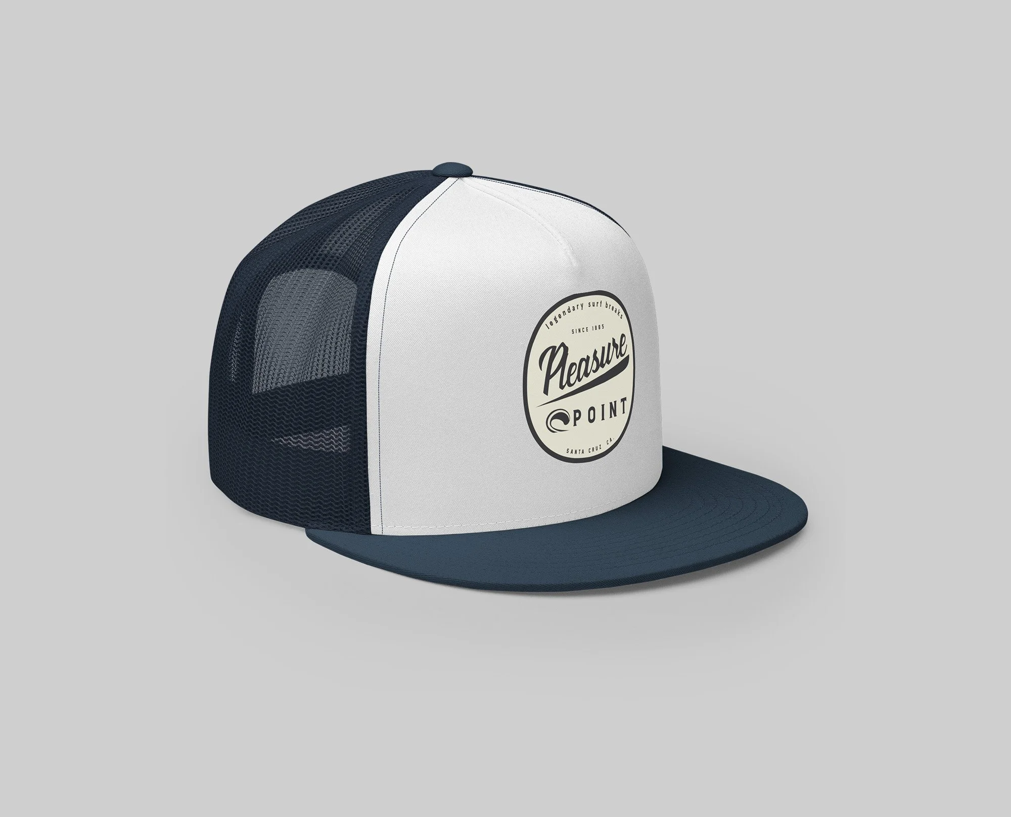 A navy and white Pleasure Point snapback trucker hat featuring a round retro-style surf badge logo that reads “Pleasure Point – Santa Cruz, CA.”