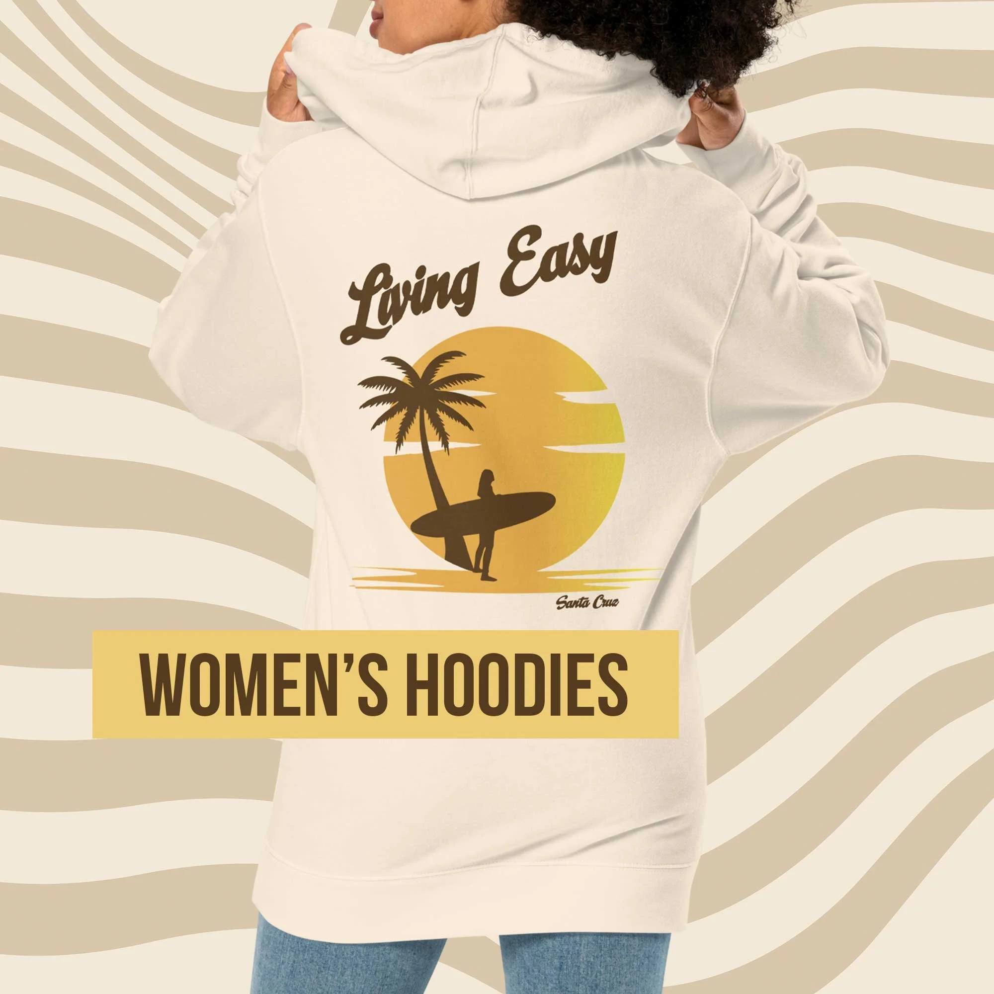 Back view of a woman wearing an off-white hoodie with a “Living Easy” Santa Cruz surf graphic featuring a surfer and palm tree, shown against a tan wavy background with a gold label reading “Women’s Hoodies.”