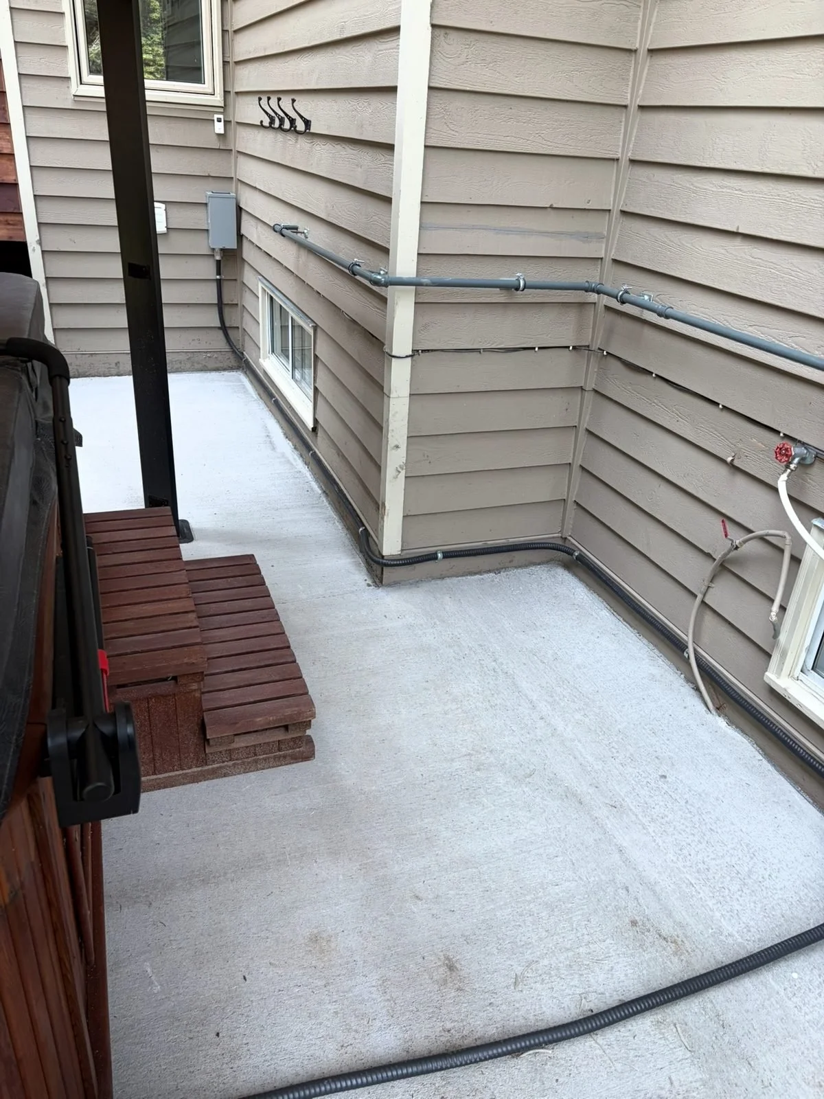 Conduit for a 50 amp hot tub circuit clipped along the siding and across the patio to the tub, installed by Koop Electrical
